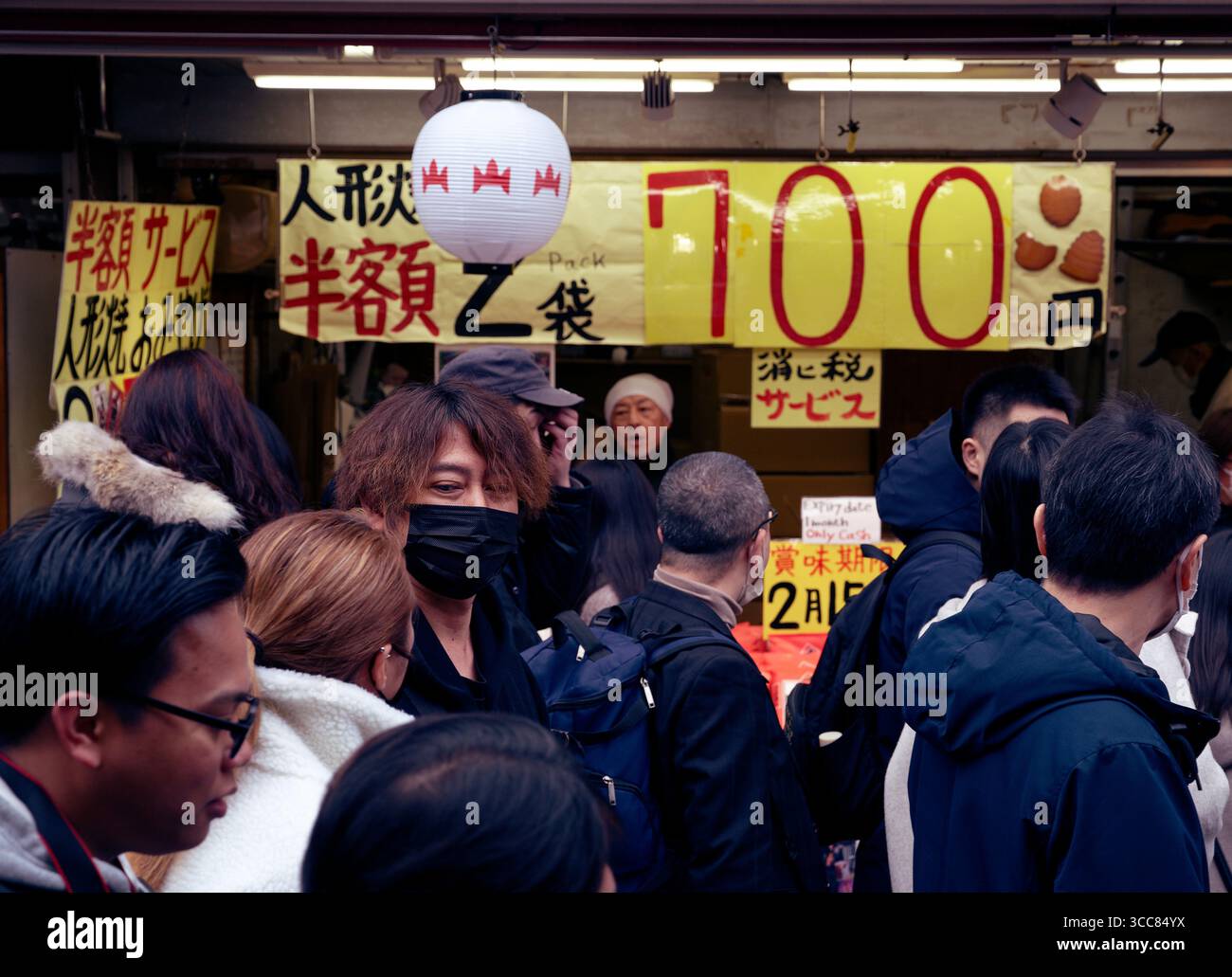 Menschenmenge, die vor einem Verkaufsstand für ermäßigte Waren in der Einkaufsstraße Nakamise läuft, mit einem Paar im Gespräch Stockfoto