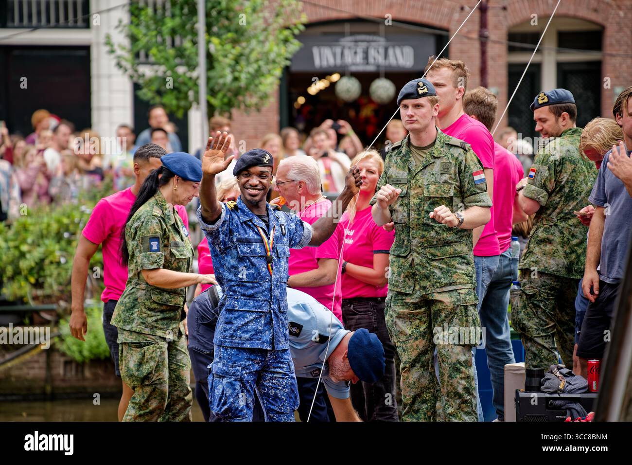 Amsterdam, Niederlande - 2. August 2025: Verteidigungspersonal feiert während der Kanalparade auf einem Boot mit Soldaten der niederländischen Marine, die der Menge zuwinken Stockfoto