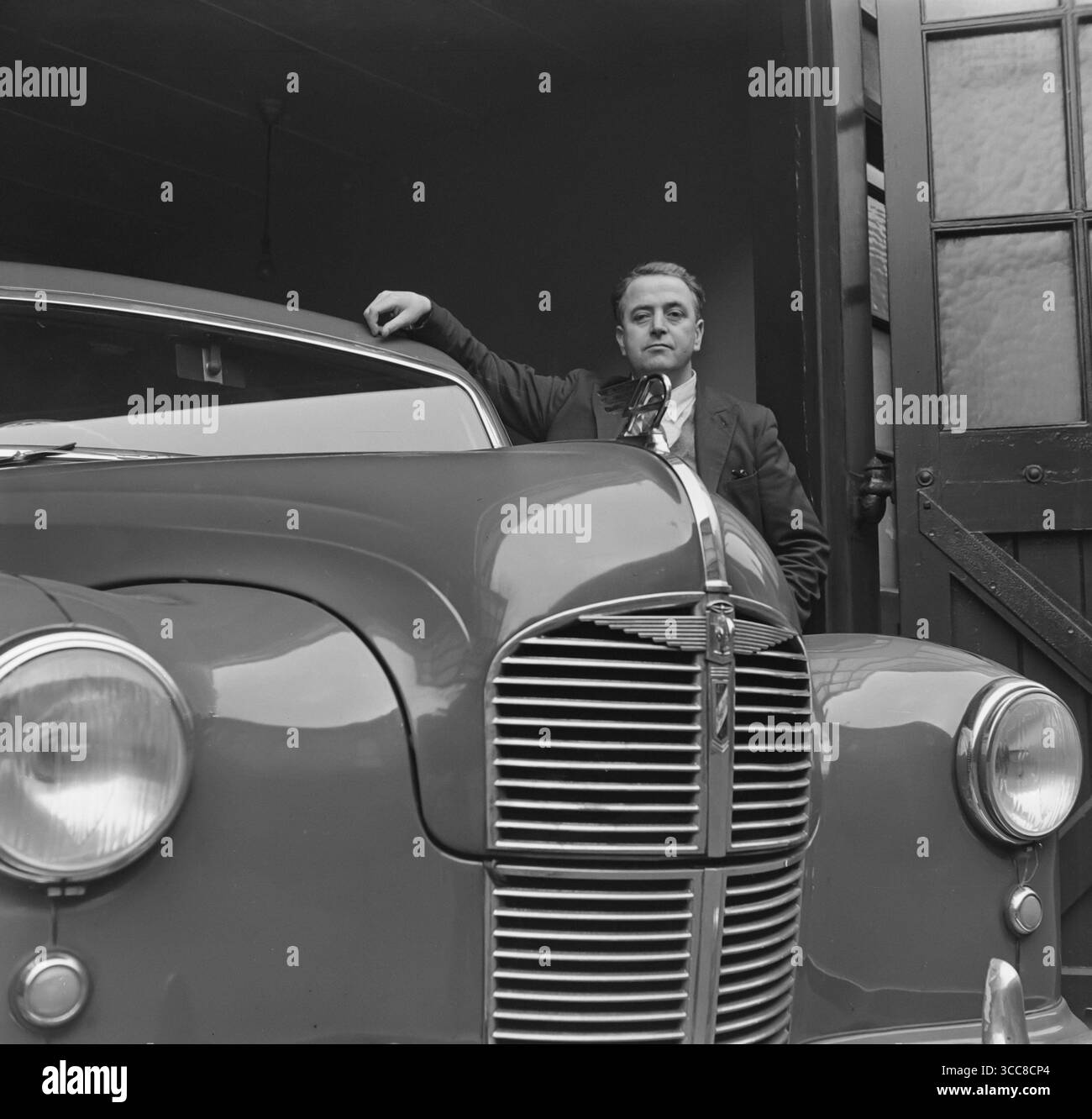 Ein klassisches Schwarz-weiß-Foto aus den 1950er Jahren, das einen Mann mit der Hand auf dem Dach eines neuen Austin A40 Devon-Autos zeigt. Stockfoto