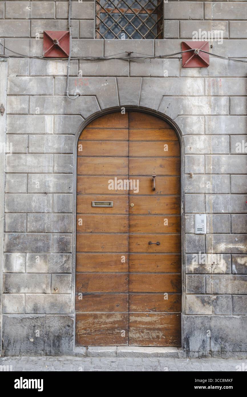Blick auf eine verwitterte Holztür, eingerahmt von grauem Stein, steht als stiller Wächter, seine alte Schönheit flüstert Geschichten aus der Zeit, Sulmona, Abruzzen, Italien. Stockfoto