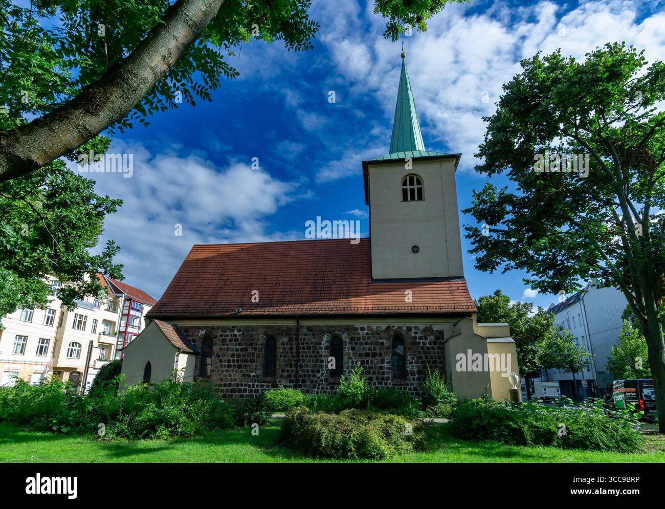 Alte Pfarrkirche Lichtenberg in Berlin, Deutschland, umgeben von Grün an einem sonnigen Sommertag. Stockfoto