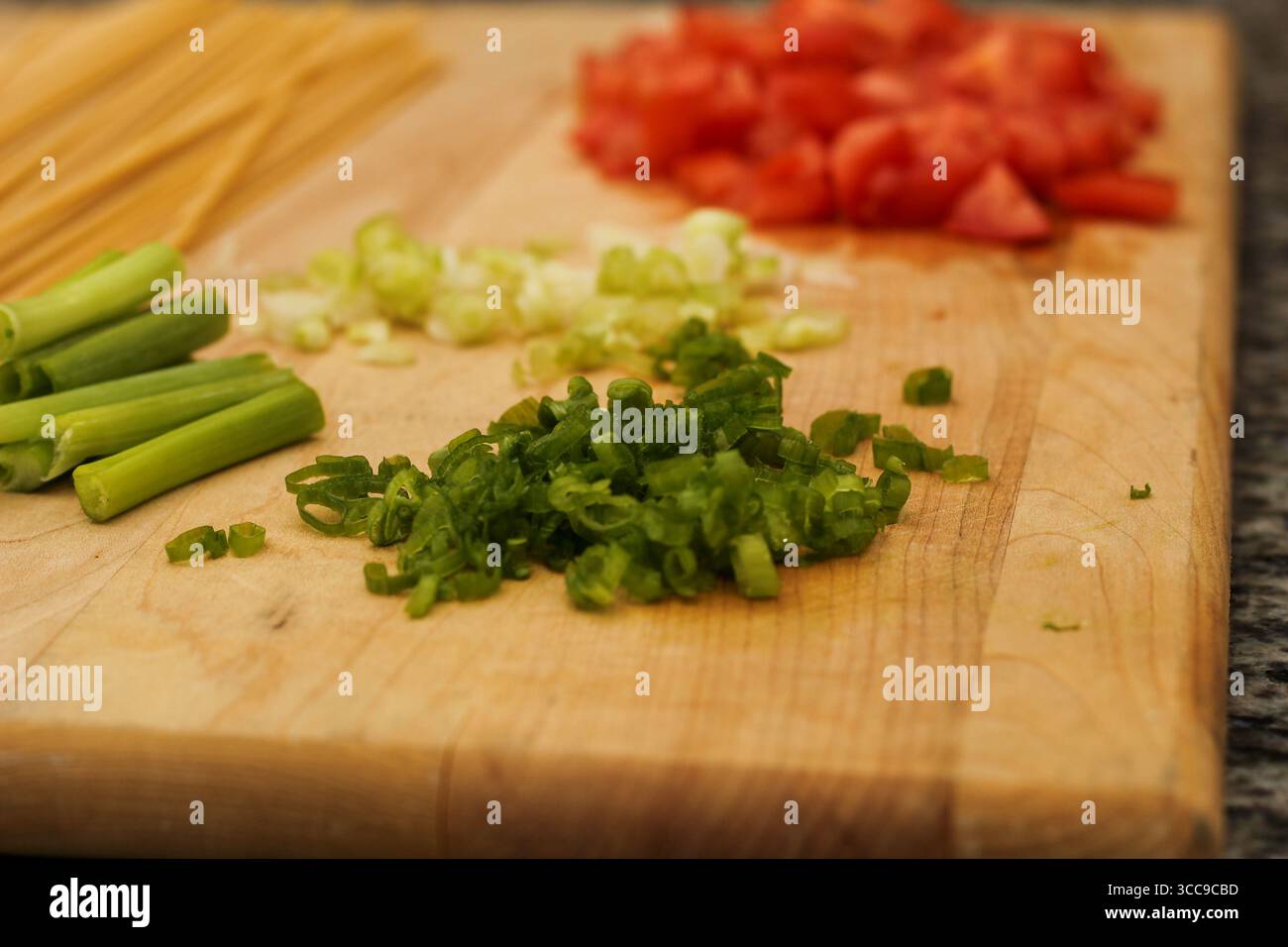 Ungekochte Pasta und frisches Gemüse auf hölzernem Schneidebrett für die Mahlzeitvorbereitung Stockfoto