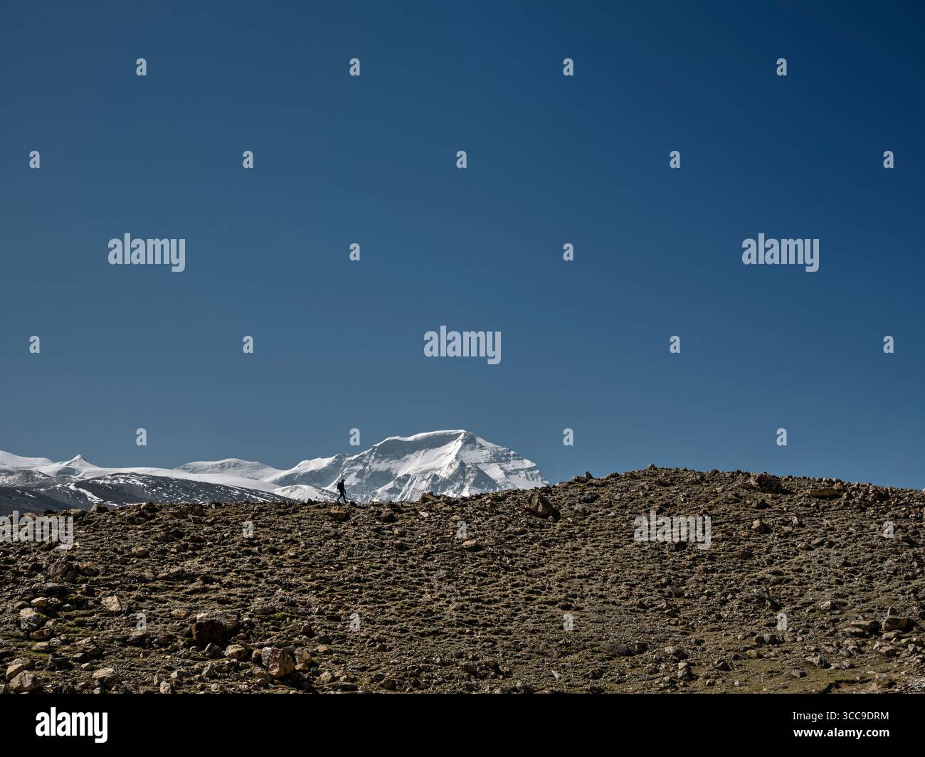 Fotograf, der auf dem Bergrücken unter dem blauen Himmel mit dem Berg Cho oyu im Hintergrund spaziert, tibet, china Stockfoto