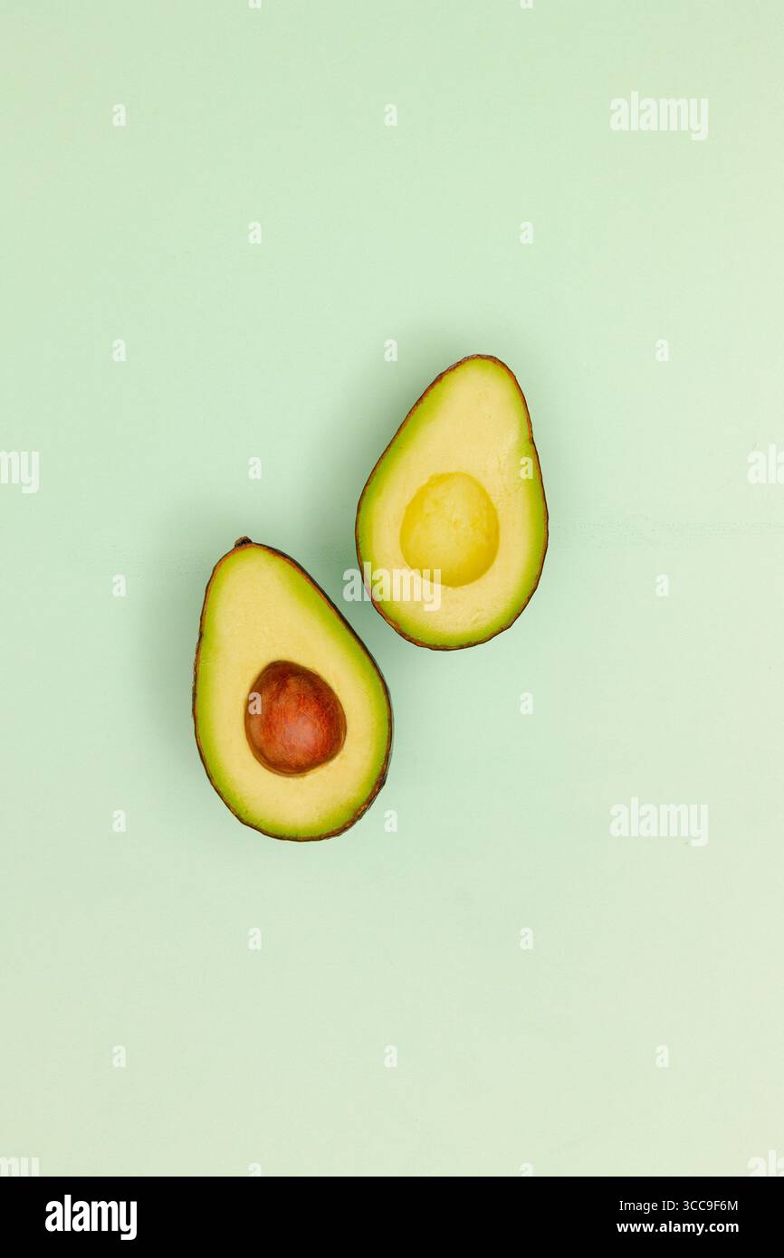 Halbe Avocado mit Grube auf grünem Hintergrund Gemüse, frische Speisen Stockfoto