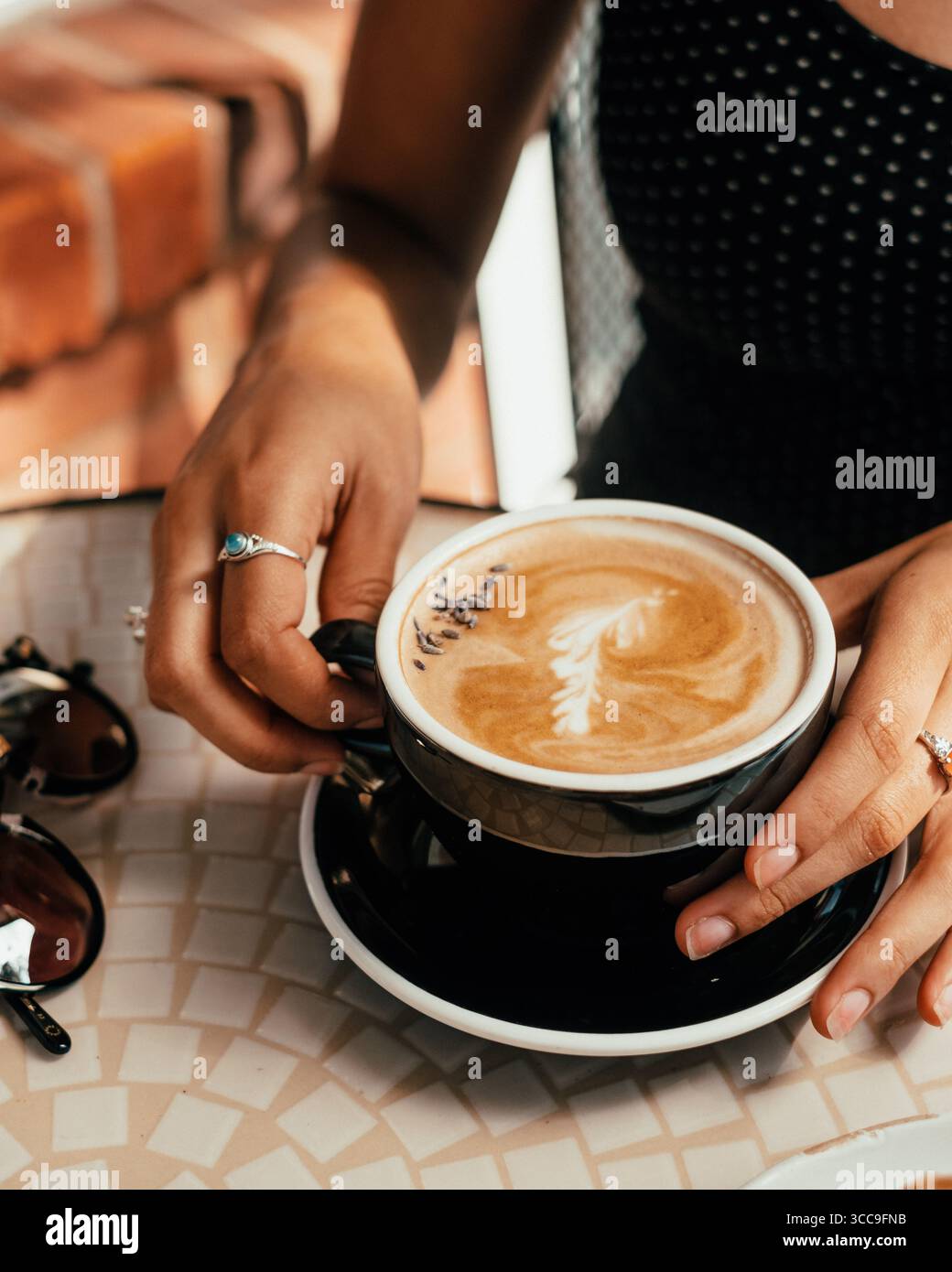 Hände halten Lavendellatte in Black Cup Stockfoto