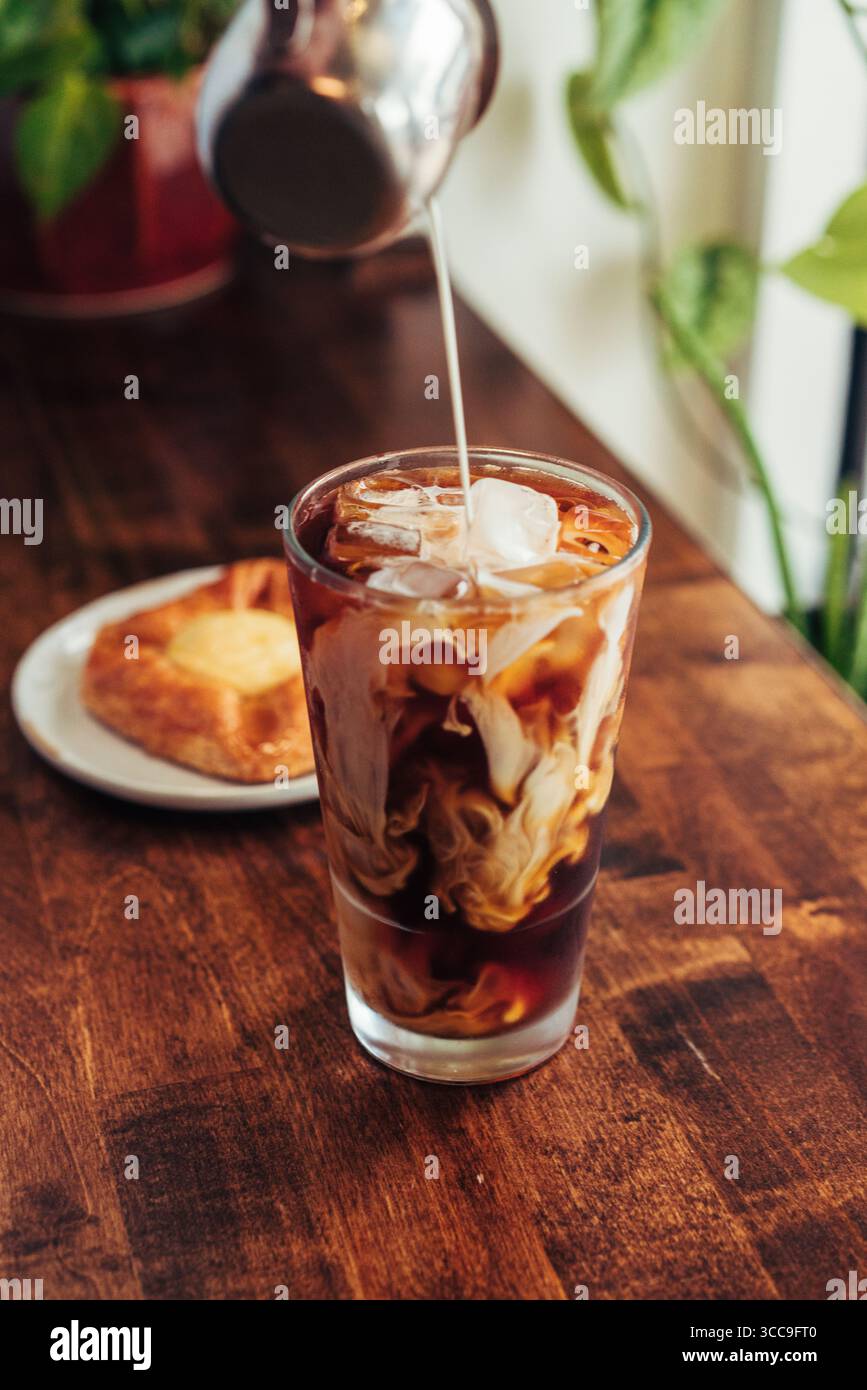 Sahne, die in Eiskaffee mit Gebäck geschwenkt wird Stockfoto