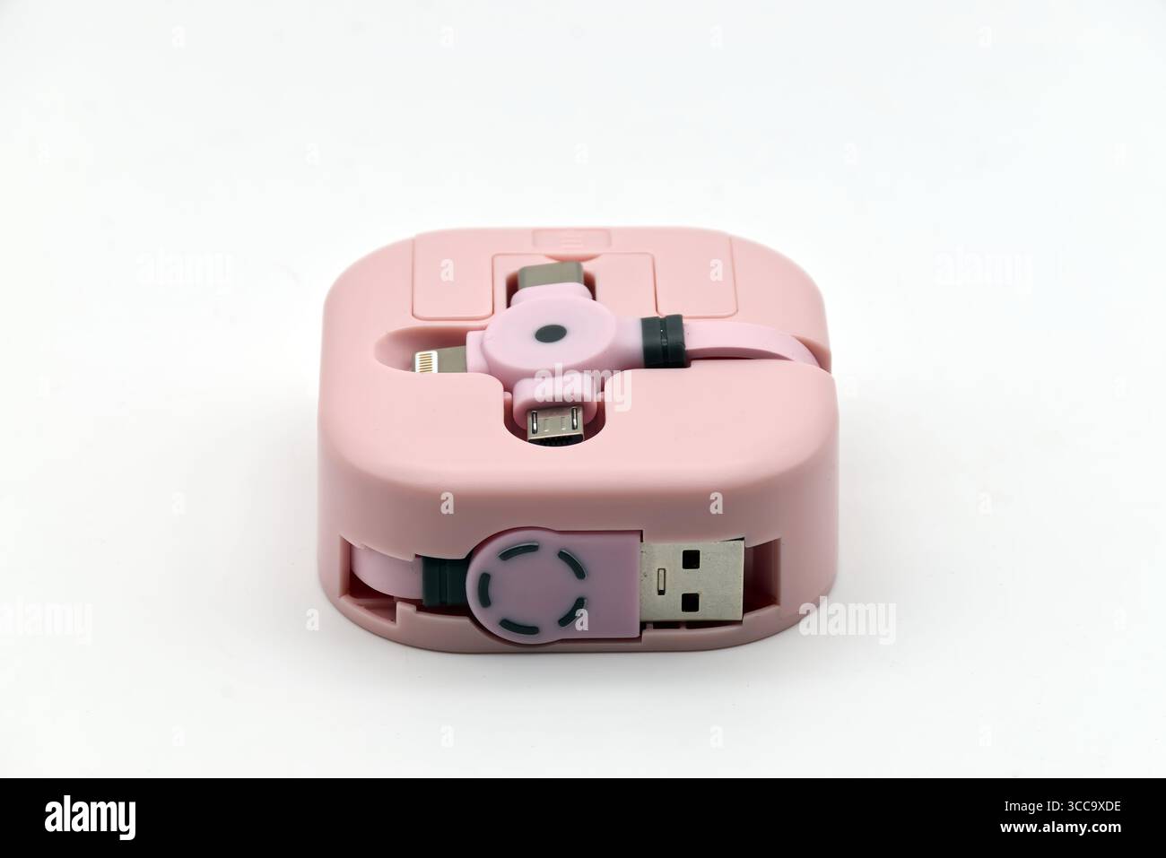 Ein pinkfarbenes tragbares Mehrfachladekabel mit verschiedenen Anschlüssen für mobile Geräte wird auf einem sauberen weißen Hintergrund präsentiert. Stockfoto