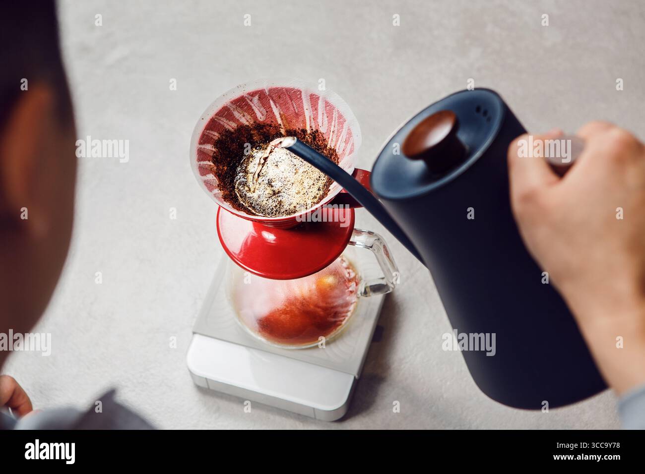 Nahaufnahme des Gießens von Wasser in den Brühtrichter zur Kaffeezubereitung Stockfoto