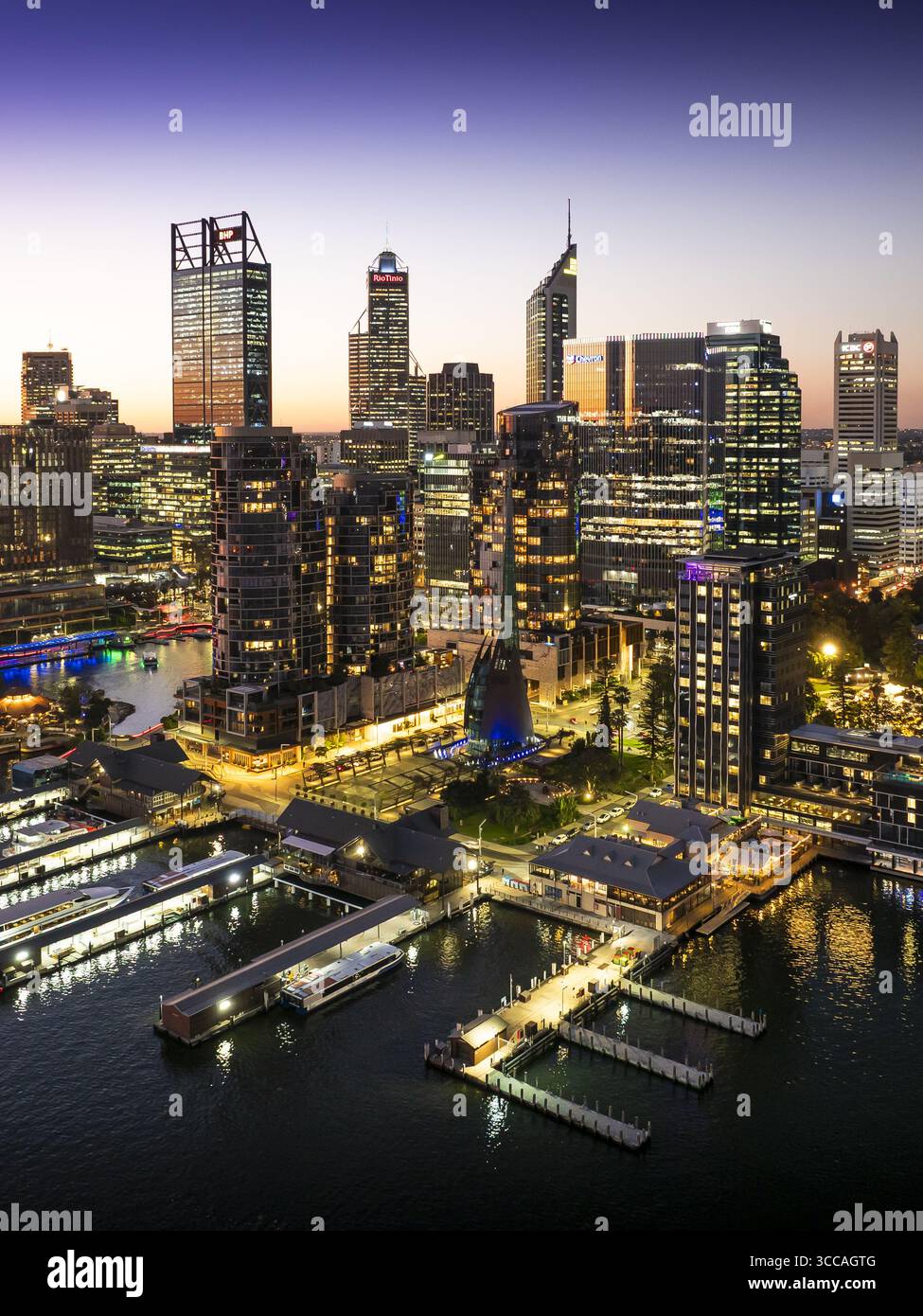Perth, Australien - 08. Juni 2025: Aus der Vogelperspektive der Esplanade erstrahlt ein leuchtendes Licht vor dem Dämmerungshimmel, das sich vom dunklen Wasser und der modernen Stadtlandschaft reflektiert. Stockfoto