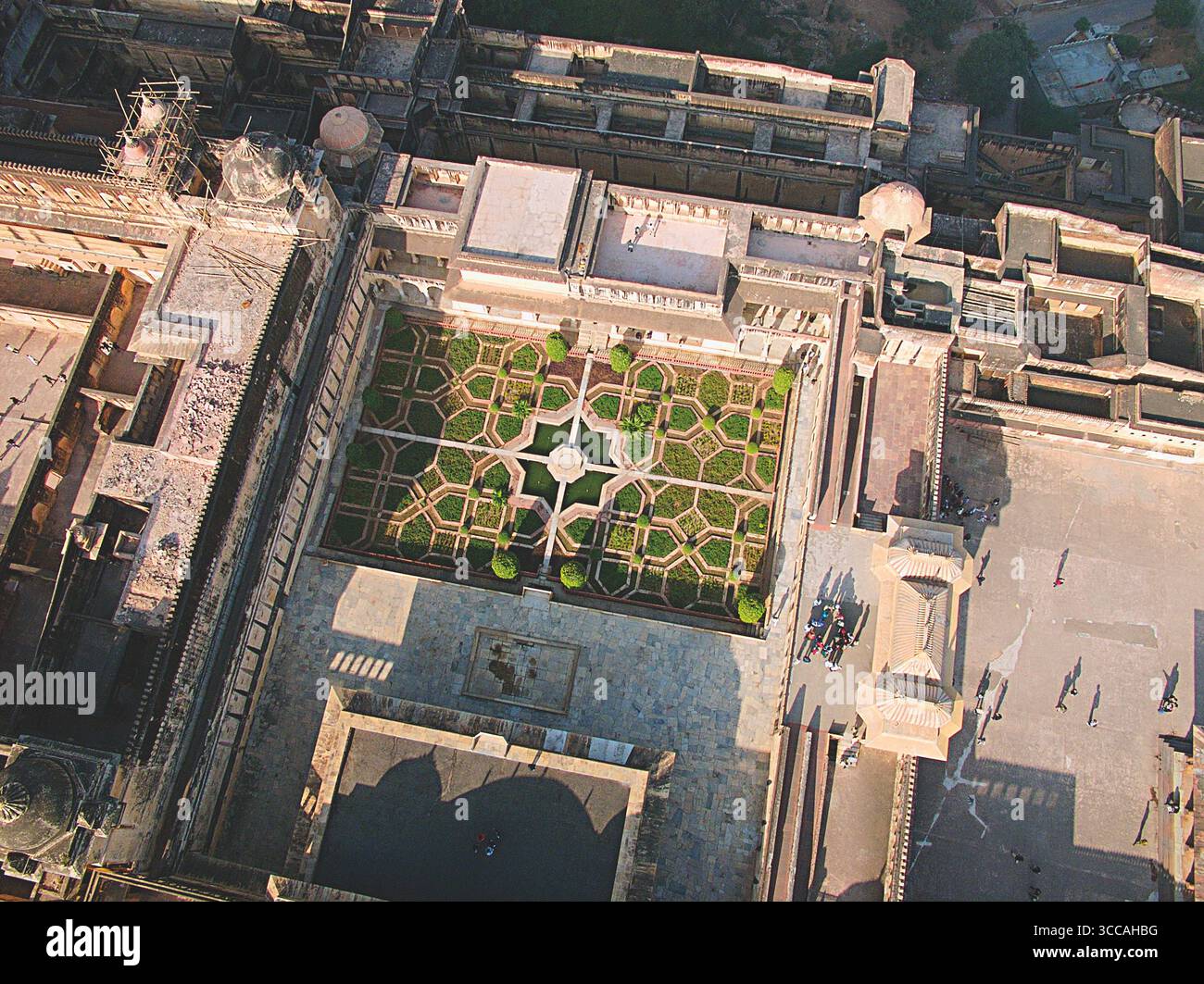 Luftaufnahme eines symmetrischen Gartens mit geometrischen Mustern, eingebettet in einen Sandsteinpalastkomplex, der Schatten im starken Sonnenlicht wirft, Jaipur, Rajasthan, Indien. Stockfoto