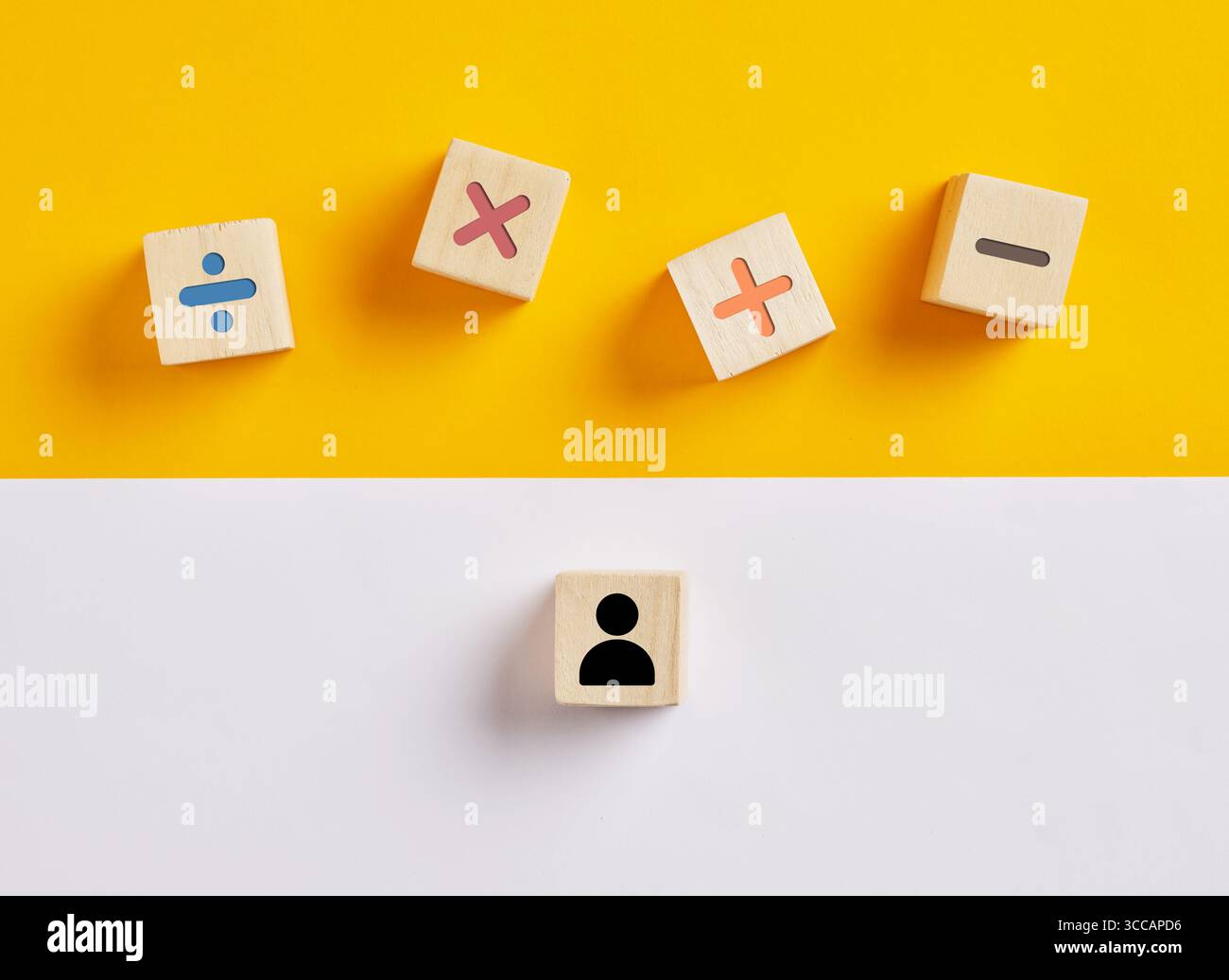 Hölzerne Würfel mit mathematischen Symbolen und ein Schüler-Icon, das die Grundausbildung von vier mathematischen Operationen darstellt. Stockfoto