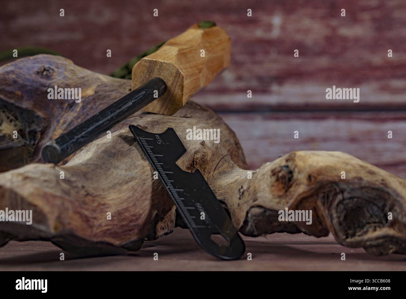 Überlebenswerkzeuge wie Ferroceriumstab, Feuerstarter und Multifunktionswerkzeug werden auf einem Stück verwittertem Holz ausgestellt und sind bereit für Outdoor-Abenteuer Stockfoto