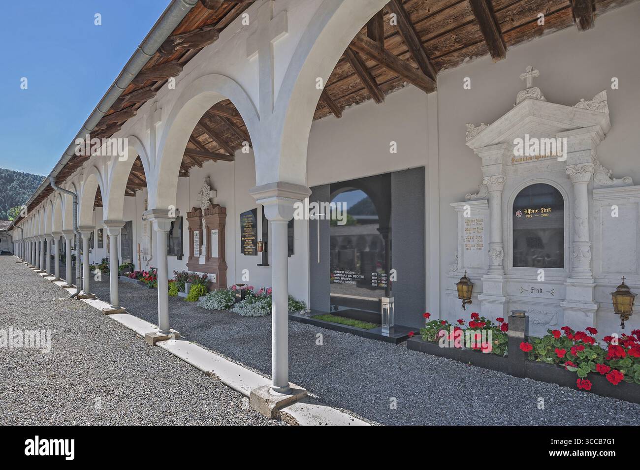 Kreuzgang mit Gräbern und Blumenschmuck auf dem Friedhof der katholischen Pfarrkirche St. drei Könige, Hittisau, Bregenzerwald, Vorarlbe Stockfoto