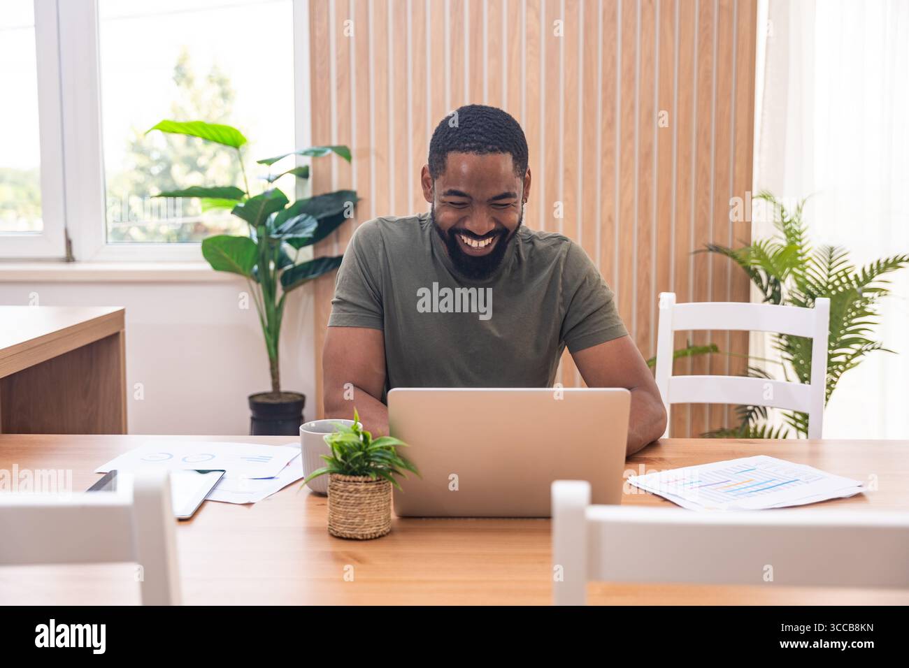 Millennial afroamerikanischer Mann, der sich während eines Webinars oder eines Geschäftstreffens Notizen macht, Laptop benutzt, online arbeitet oder studiert, zuhause am Schreibtisch sitzt Stockfoto
