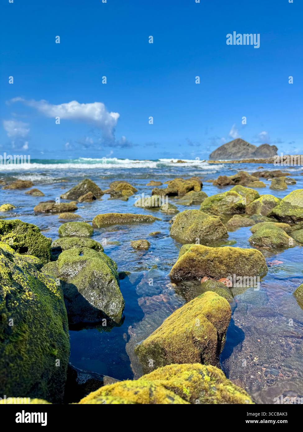 Ebbe am Strand von Mosteiros, Azoren, Portugal, mit grünen Vulkanfelsen und den berühmten Mosteiros-Inseln in der Ferne. - Smartphone-aufgenommenes Stockfoto