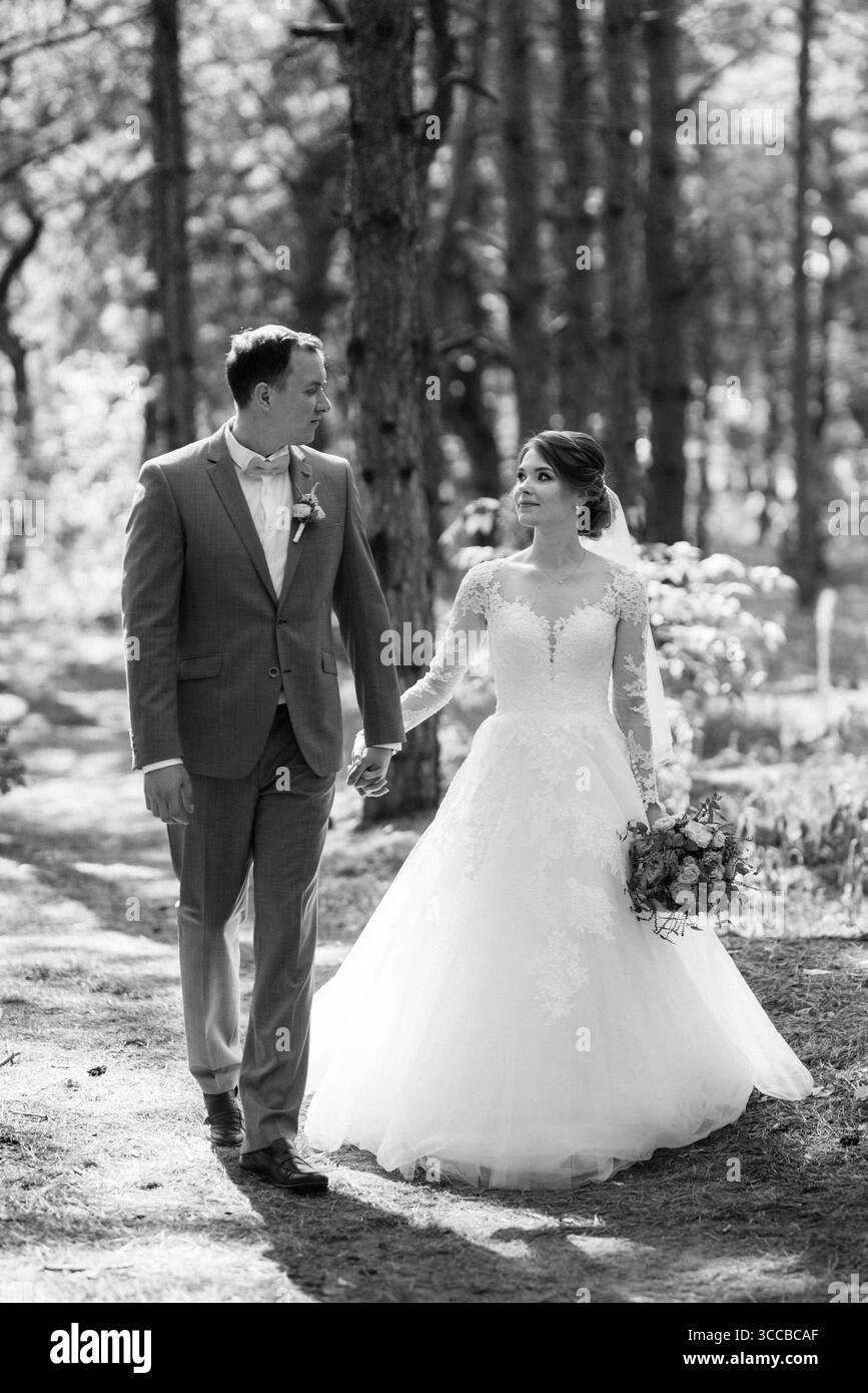 Porträt eines eleganten Bräutigams im blauen Anzug in einem Laubwald mit einem Blumenstrauß Stockfoto