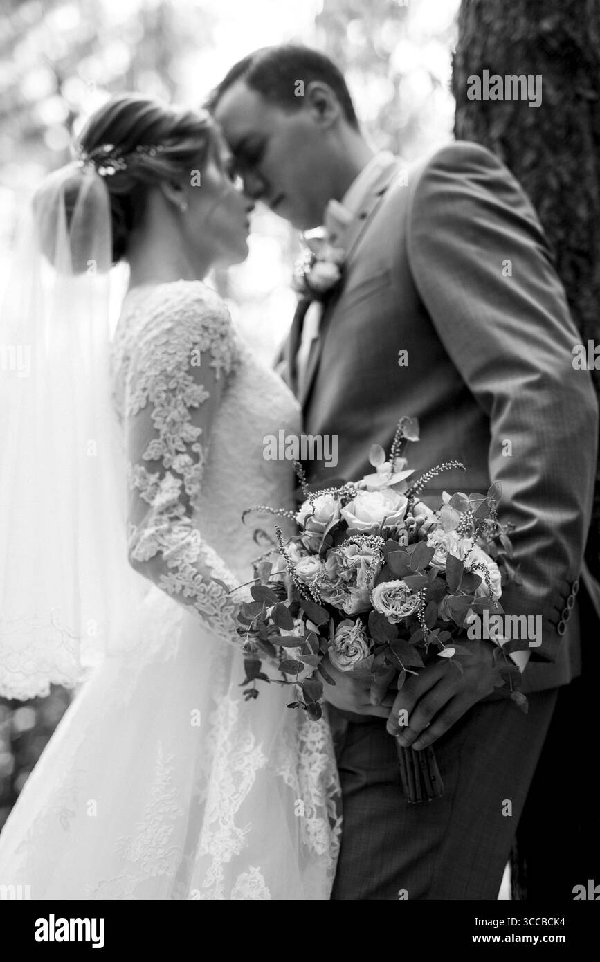 Porträt eines eleganten Bräutigams im blauen Anzug in einem Laubwald mit einem Blumenstrauß Stockfoto