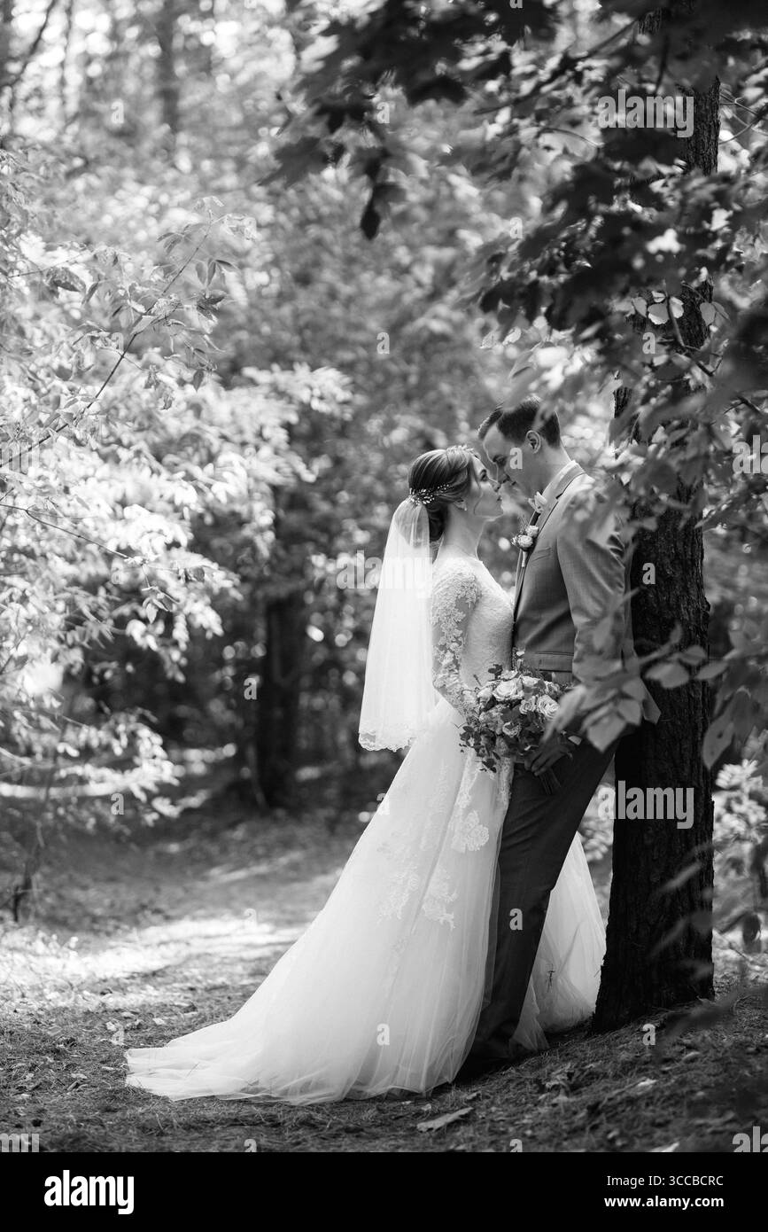 Porträt eines eleganten Bräutigams im blauen Anzug in einem Laubwald mit einem Blumenstrauß Stockfoto