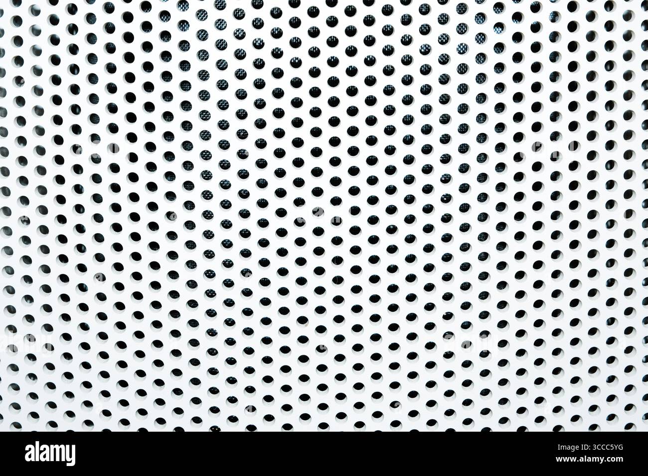 Nahaufnahme einer perforierten Metalloberfläche mit geometrischem Muster aus kreisförmigen Löchern Stockfoto