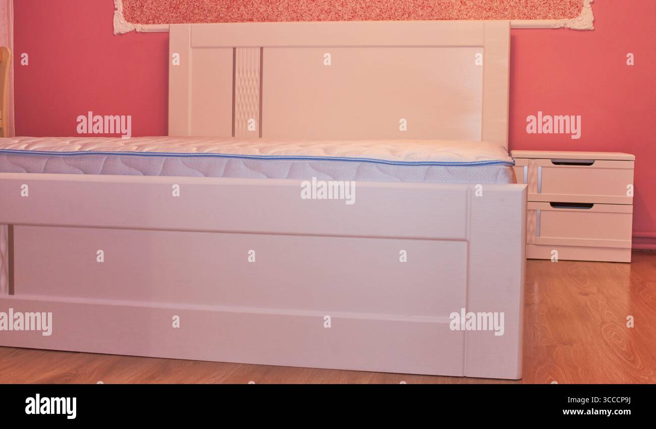 Schlafzimmer mit weißem Bett und Matratze, rosafarbenes Zimmer mit weißem Bett Stockfoto