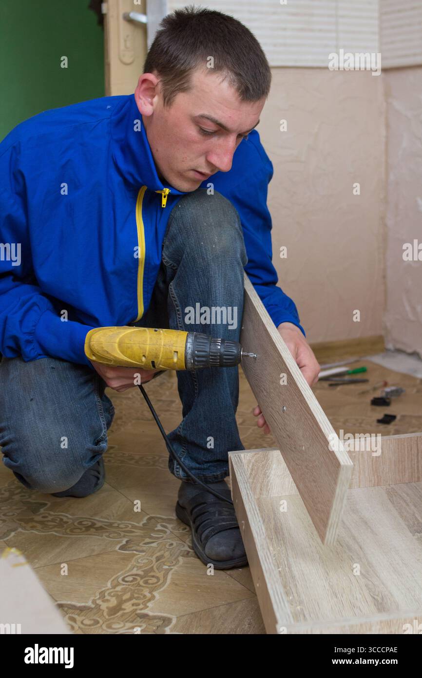 Arbeiter bohrt ein Loch, wenn Möbel montiert werden Stockfoto