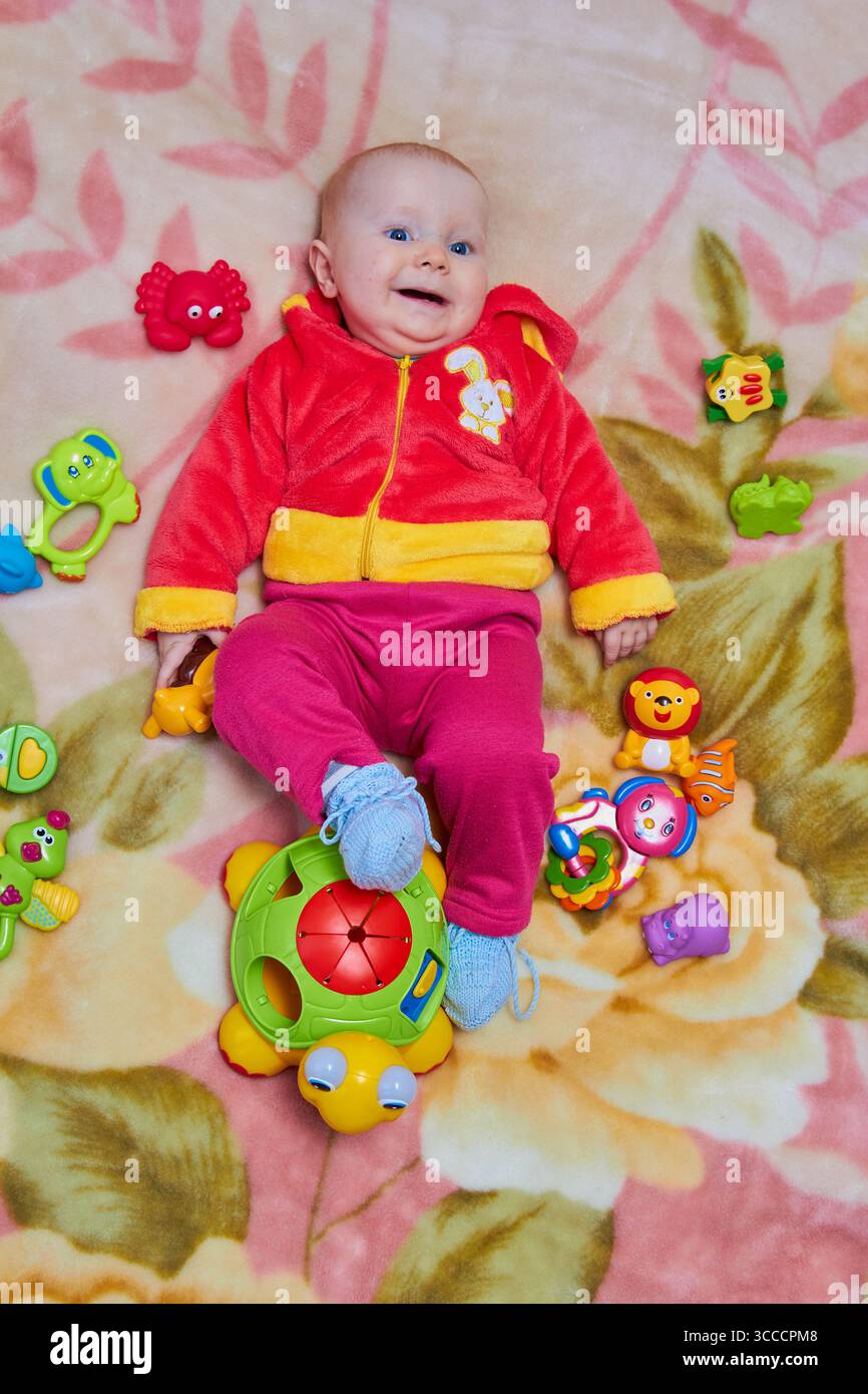 Auf dem Bett liegend, Baby mit Blick von oben auf das Spielzeug Stockfoto
