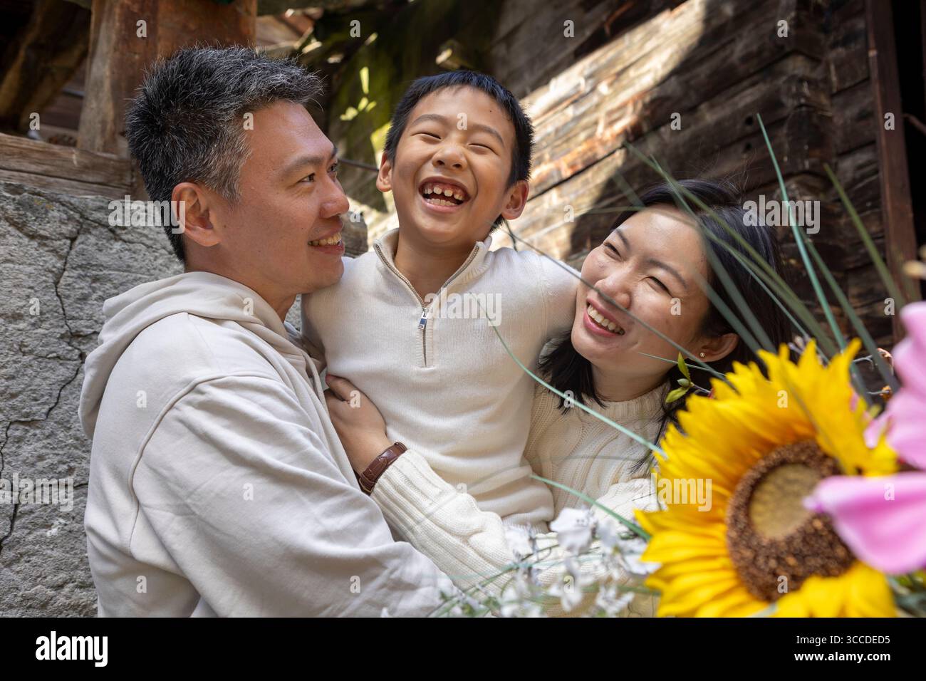 Glückliche asiatische Familie umarmt und lächelt in die Kamera Stockfoto
