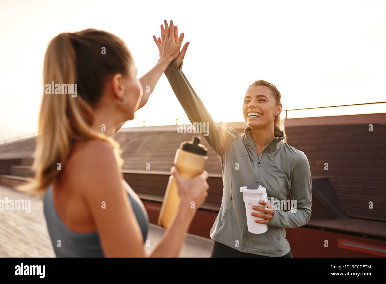 Zwei glückliche Freunde feiern ihr lohnendes Workout mit einem highfive, zeigen ihre Freundschaft und Fitness-Leidenschaft und inspirieren andere dazu, ein HE anzunehmen Stockfoto