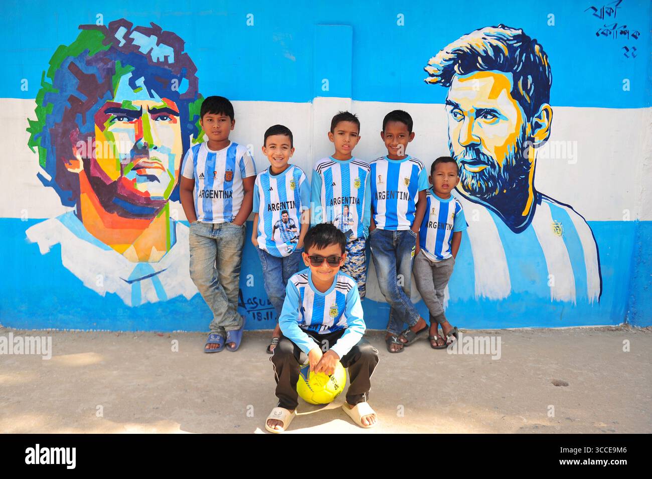8. Dezember 2022, Sylhet, Bangladesch: 8. Dezember 2022 Sylhet-Bangladesch: Argentinien-Fans posieren auf der Straße von Sylhet, vor dem Gemälde Graffiti von DIEGO MARADONA und LIONEL MESSI von Argentinien. Bangladesch, ein solches Land, das nie für eine Fußball-Weltmeisterschaft qualifiziert wurde, aber große Liebe zum Fußball hat und riesige Fans sowohl für Argentinien als auch für Brasilien hat. (Bild: © MD Rafayat Haque Khan/ZUMA Press Wire) Stockfoto