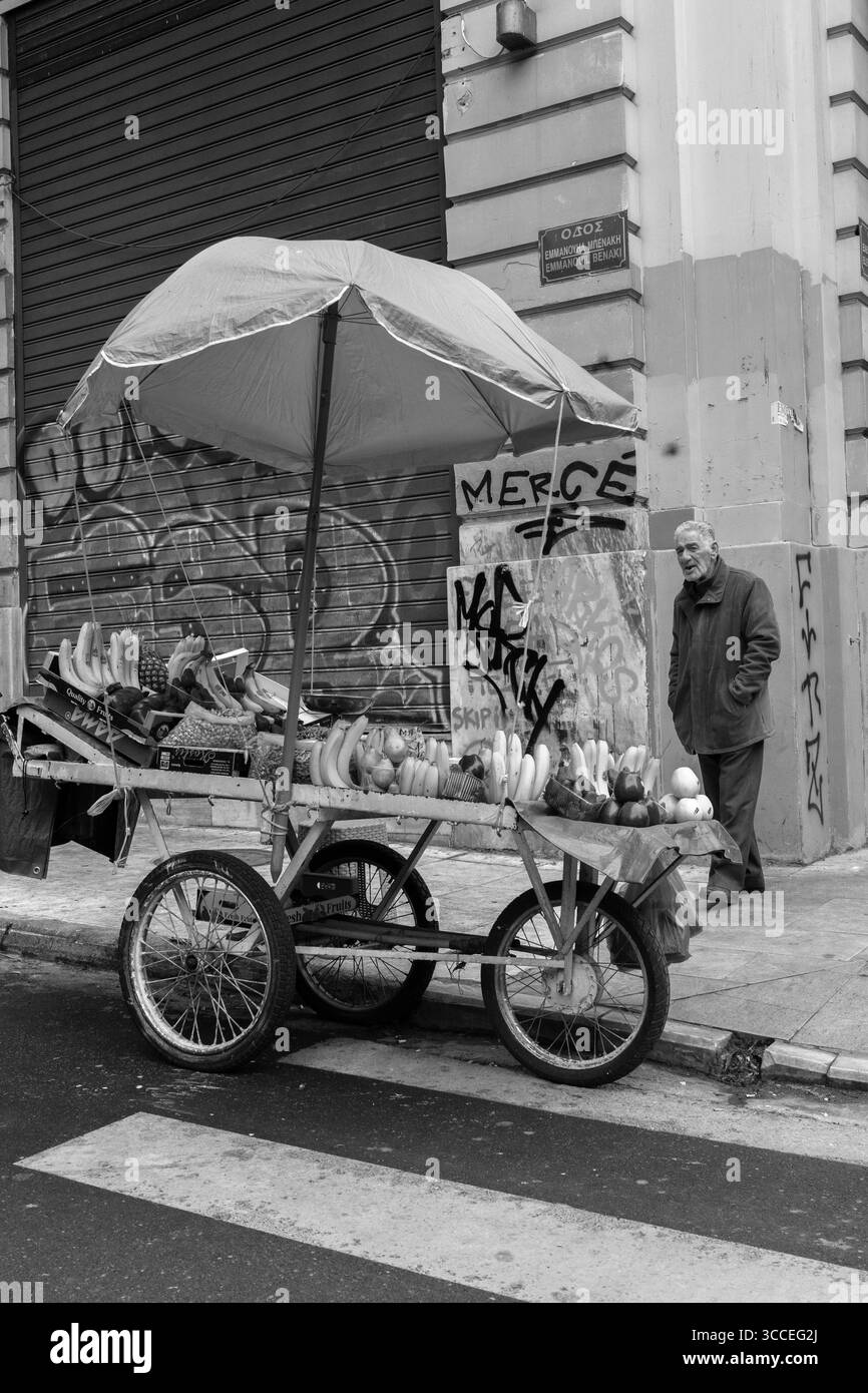 Blick auf die Straße, Nahaufnahme eines Mannes, der Obst an einem belebten Straßenstand in Athen, Griechenland, arrangiert. Stockfoto