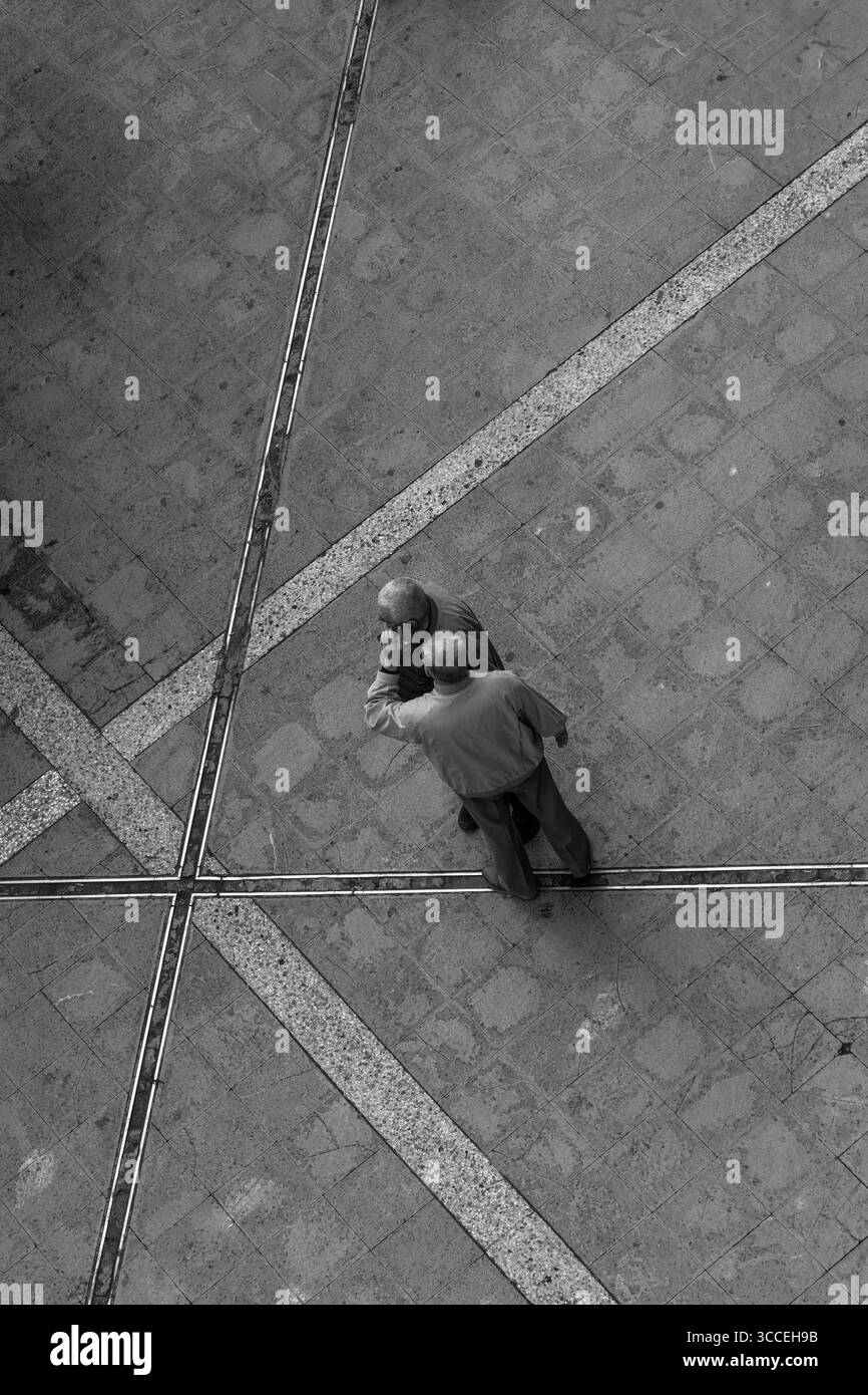 BirdsEye-Ansicht von zwei Männern, die ein Smartphone bei einem Anruf teilen, Straßenruf, vom Hotelfenster aus gesehen, Athen, Griechenland Stockfoto