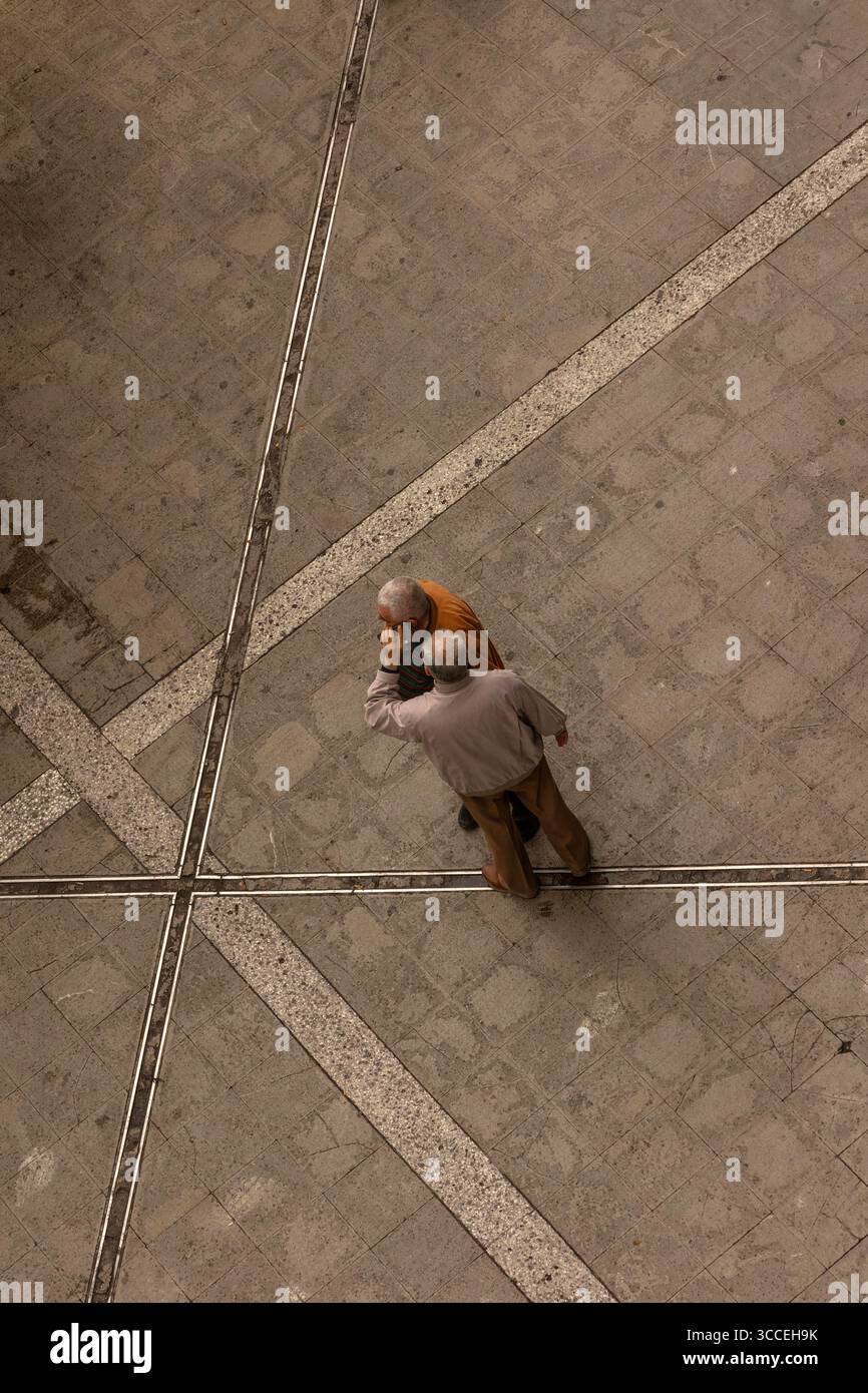 BirdsEye-Ansicht von zwei Männern, die ein Smartphone bei einem Anruf teilen, Straßenruf, vom Hotelfenster aus gesehen, Athen, Griechenland Stockfoto