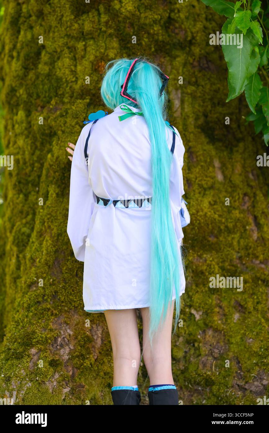 Junge Frau mit blauem Haar, die moosigen Baum berührt Stockfoto