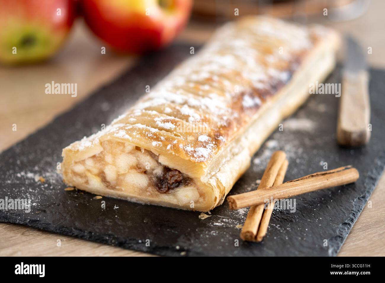 Frisch gebackener hausgemachter Apfelstrudel auf einem schwarzen Schieferbrett. Stockfoto