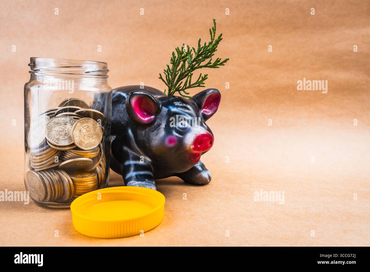 Spar- und Wachstumsschwein und Münzen in einem Glas mit festem Boden Stockfoto