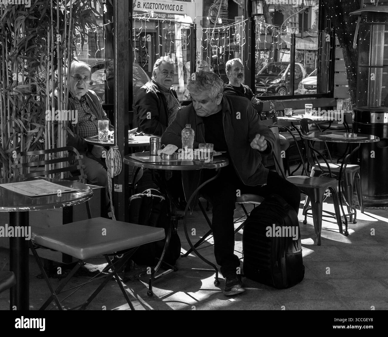 Eine Gruppe älterer Männer genießt ein traditionelles griechisches Mittagessen im Freien in einer Taverne in Athen, Griechenland, mediterranen Lebensstil, Kultur und geselliges Treffen Stockfoto