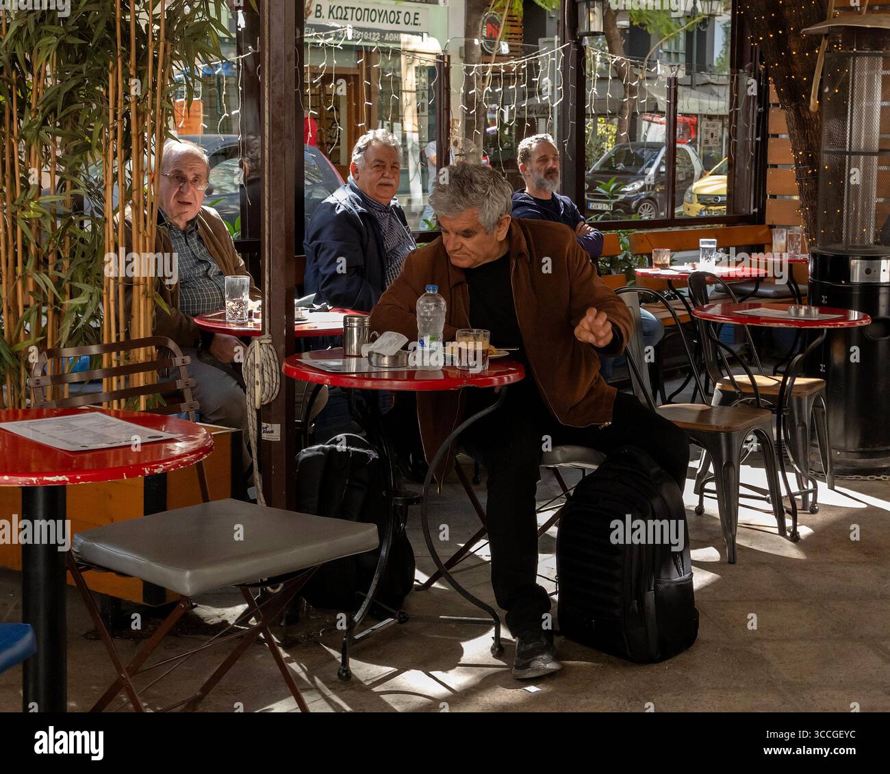 Eine Gruppe älterer Männer genießt ein traditionelles griechisches Mittagessen im Freien in einer Taverne in Athen, Griechenland, mediterranen Lebensstil, Kultur und geselliges Treffen Stockfoto