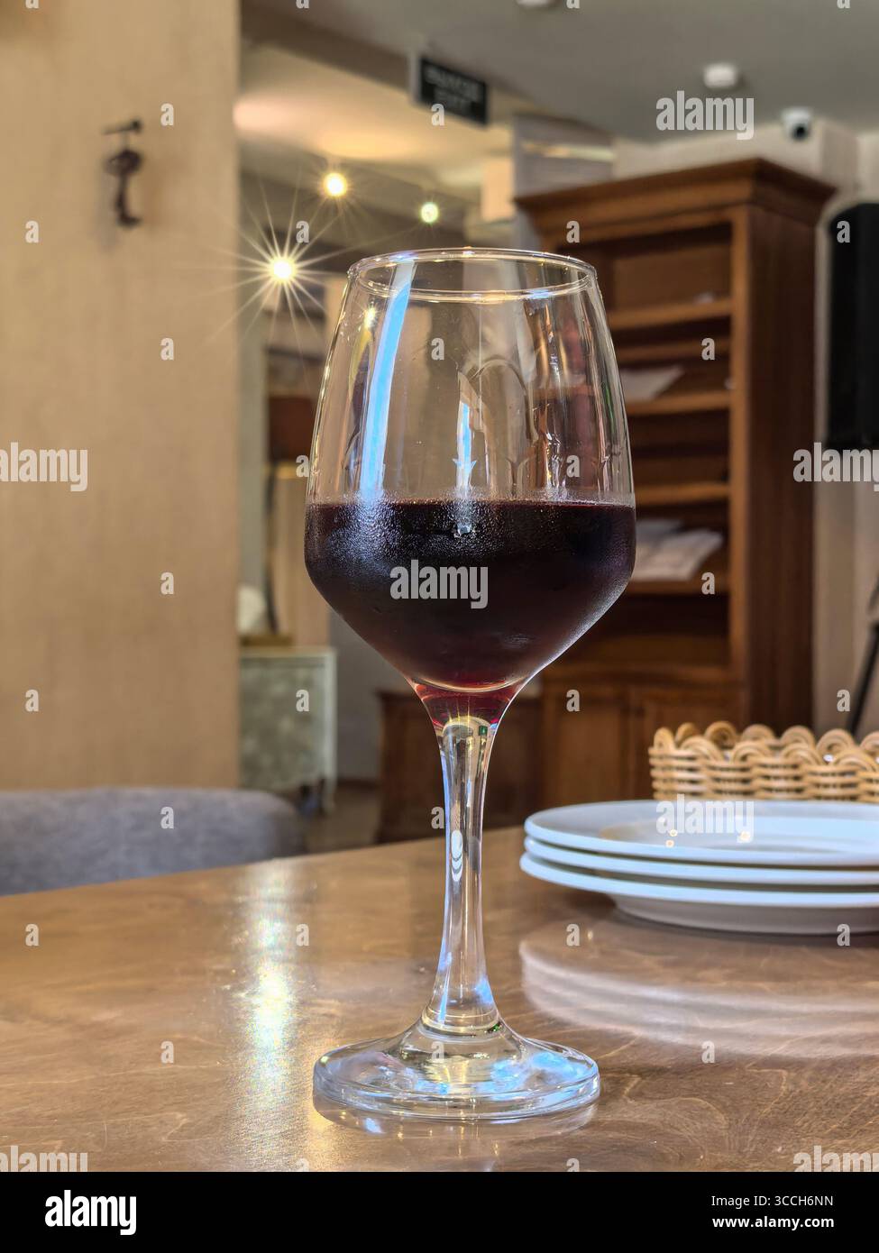 Elegantes Glas Rotwein auf dem Tisch in einer gemütlichen Café-Atmosphäre Stockfoto
