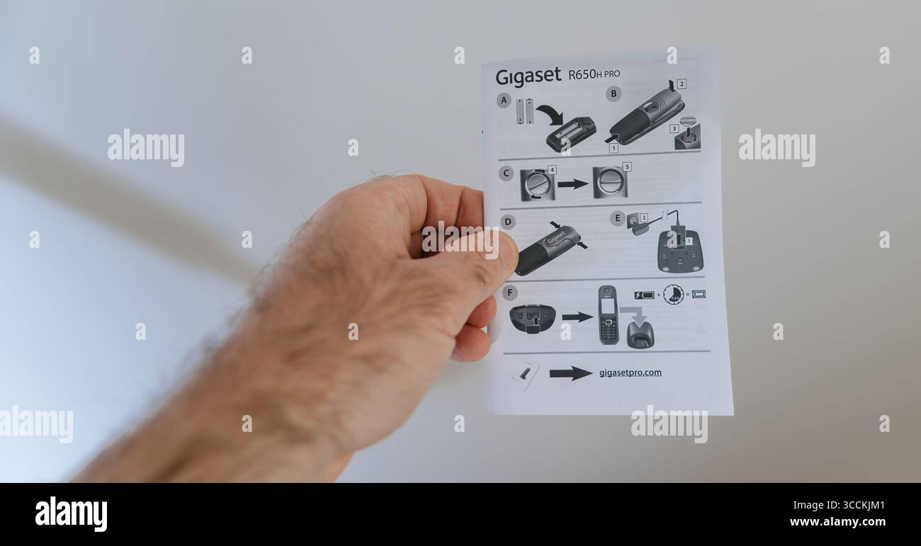 München, Deutschland - 28. März 2025: Kurzanleitung zur Installation des Gigaset R650H pro in einer Hand gehalten und mit visuellen Schritten zum Einlegen der Batterie dargestellt Stockfoto