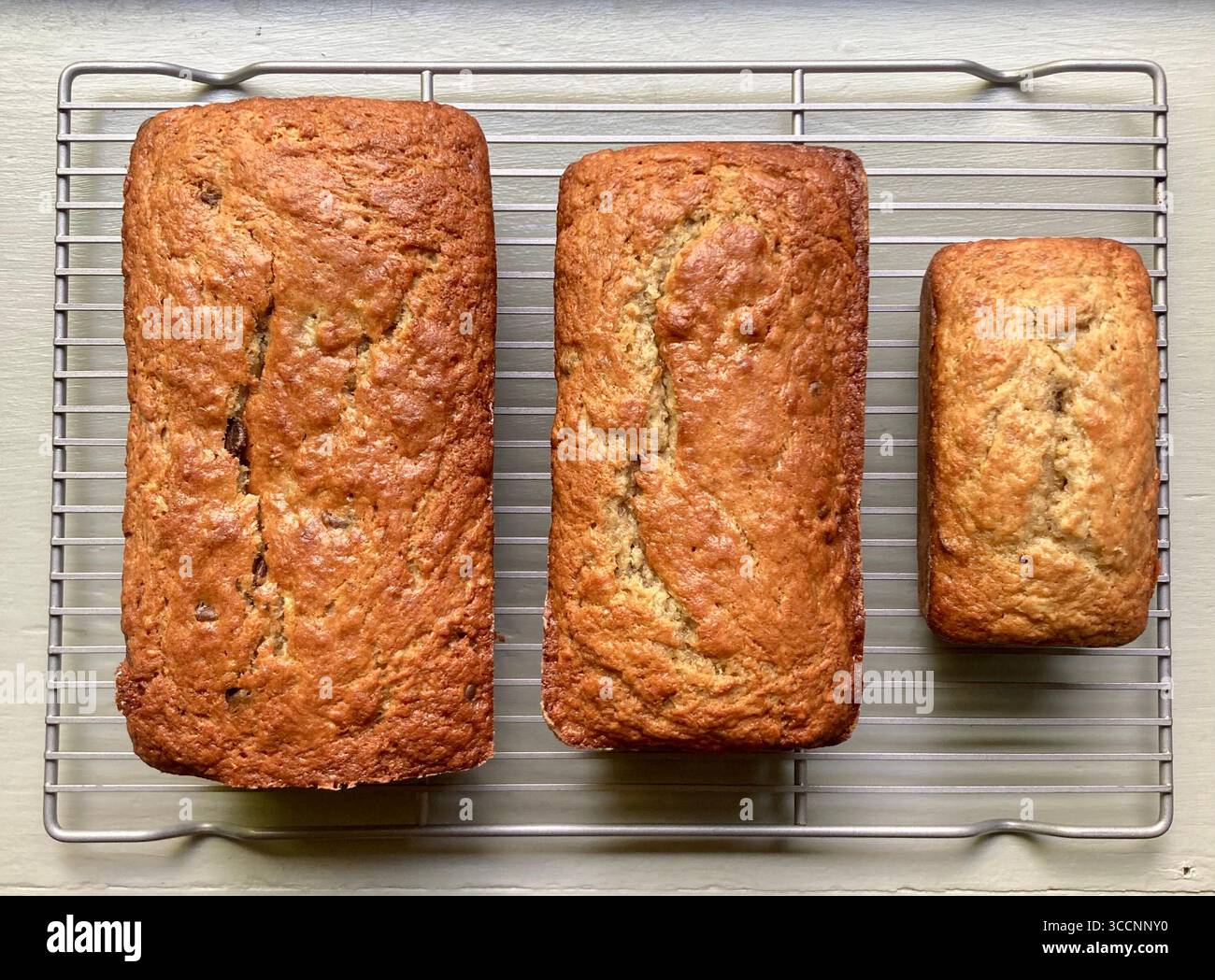 3 verschiedene Größen von Bananenbrot kühl auf einem Rack. - Smartphone-aufgenommenes Stockfoto