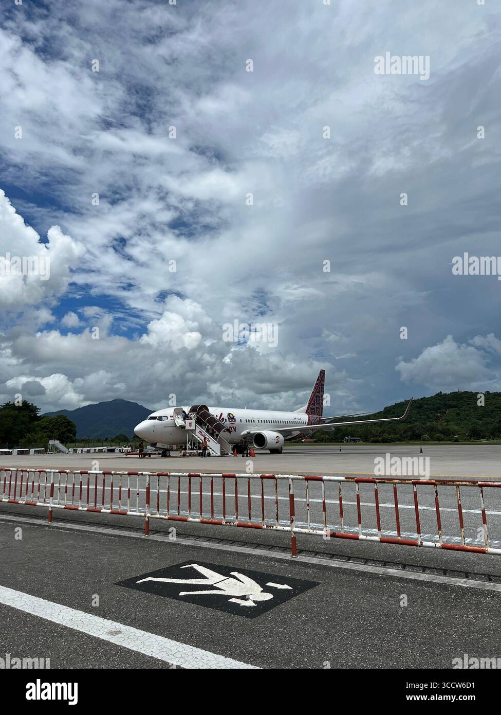 Ein Passagierflugzeug auf der Landebahn am Flughafen Langkawi, Malaysia, unter einem dramatisch bewölkten Himmel. Stockfoto Ein Passagierflugzeug auf der Landebahn am Flughafen Langkawi, Malaysia, unter einem dramatisch bewölkten Himmel. Stockfoto