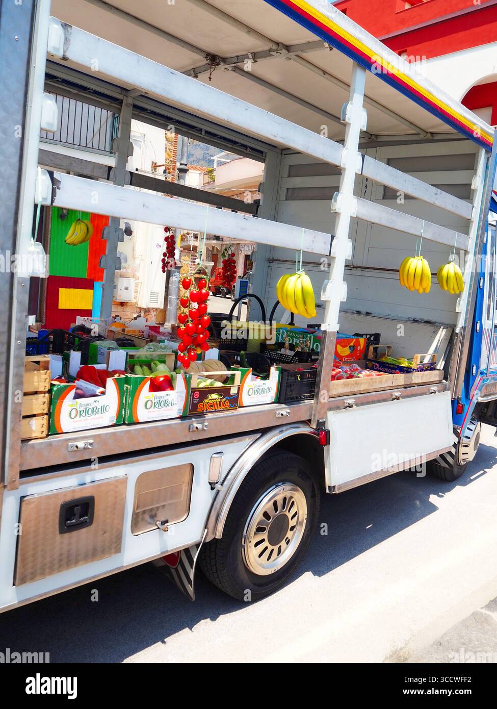 Obst- und Gemüsewagen, der die Straße mit Bananen und Tomaten in Taormina Sizilien, Italien, überquert Stockfoto