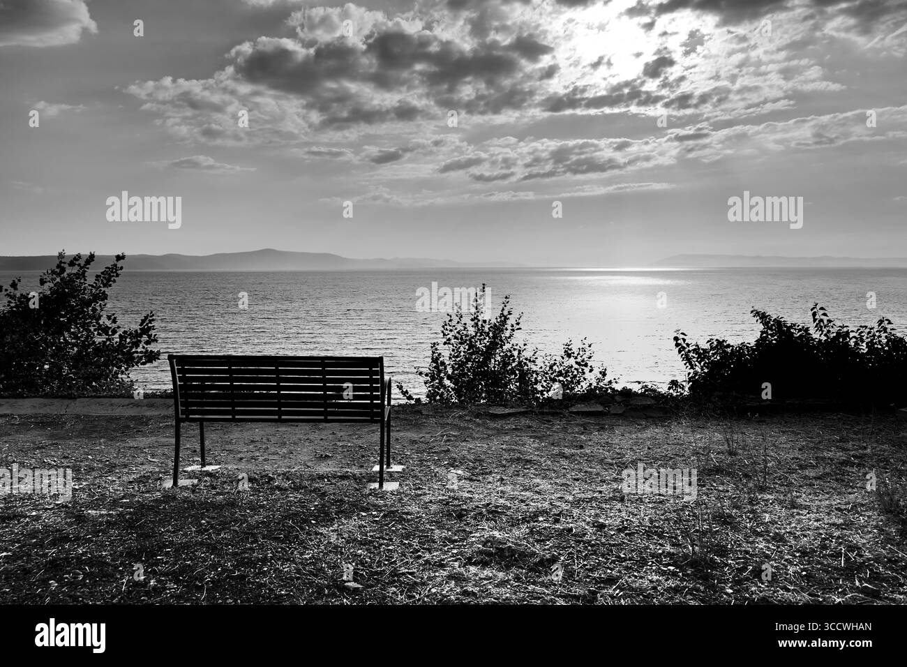 Ruhiger Schwarzweiß-Blick auf eine leere Bank mit Blick auf die Adria in Živogošće nahe Igrane an der dalmatinischen Küste in Kroatien Stockfoto