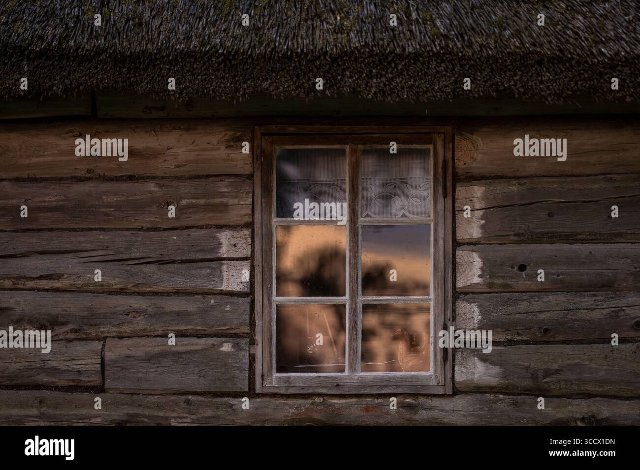 Rustikale Blockhütte und Fenster mit einer Reflexion des Sonnenaufgangs. Altes Holzhaus Fenster Hintergrund. Stockfoto