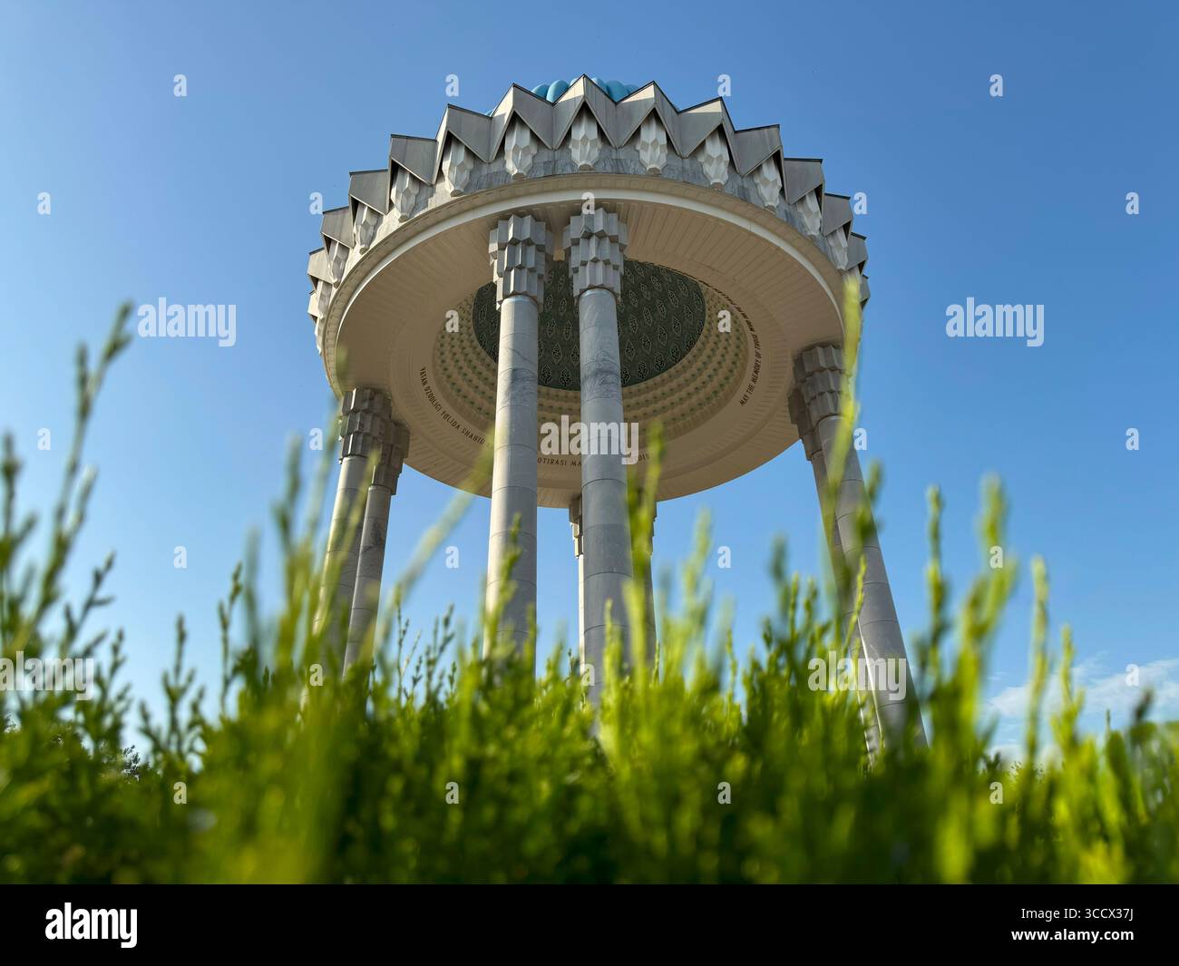 Gedenkdenkmal mit Marmorsäulen und komplizierter Kuppel in Taschkent, Usbekistan, vor einem hellblauen Himmel mit grünem Vordergrund Stockfoto