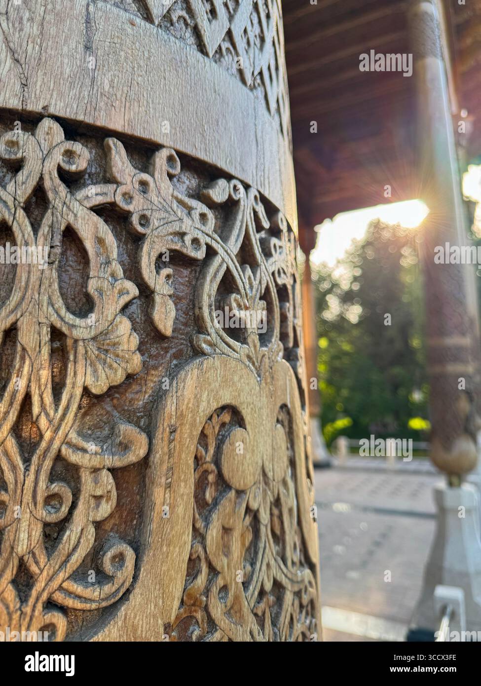 Detaillierte Nahaufnahme komplizierter traditioneller Holzschnitzereien auf einer dekorativen Säule bei warmem Sonnenlicht. Die Handwerkskunst spiegelt das kulturelle Erbe und die Geschichte wider Stockfoto