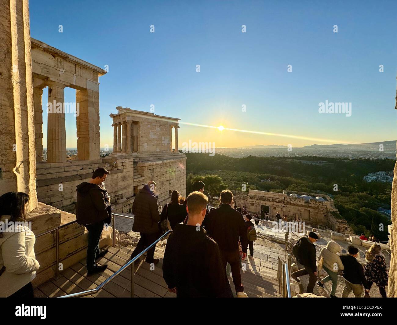 Goldene Stunde Sonnenuntergang am Eingang des Akropolis-Komplexes (Acrópole Propileia) in Athen, Griechenland, mit Touristen, die die Treppe hinunter laufen. Stockfoto