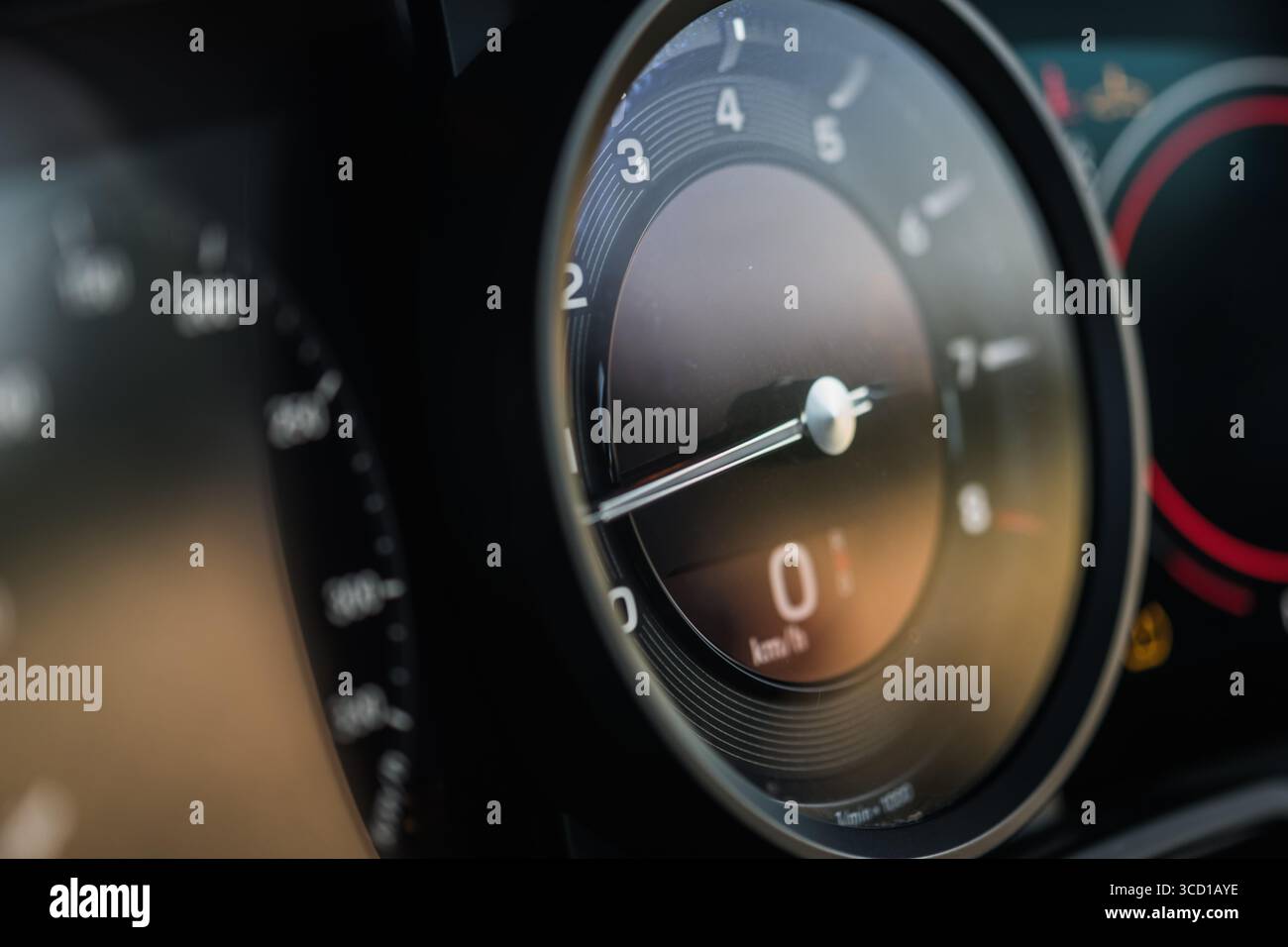 Aus nächster Nähe ein Tachometer und ein Armaturenbrett mit präzisen Details der Instrumente des Luxusautos, während sich das Sonnenlicht auf der Oberfläche reflektiert. Stockfoto