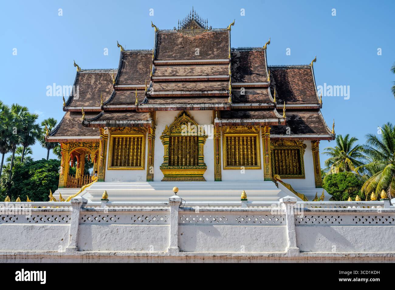 Verzierte traditionelle buddhistische Tempel mit goldenen Details in Luang Prabang, Laos unter klarem blauen Himmel Stockfoto