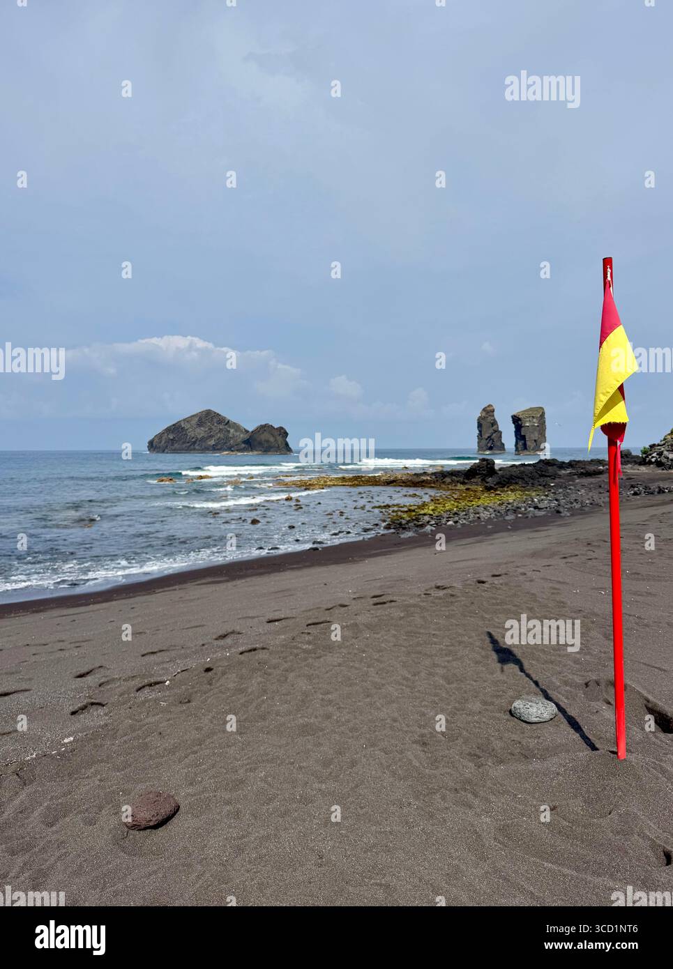 Rote und gelbe Rettungsfahne, die einen überwachten Badebereich am Strand von Mosteiros auf den Azoren, Portugal, anzeigt. Stockfoto